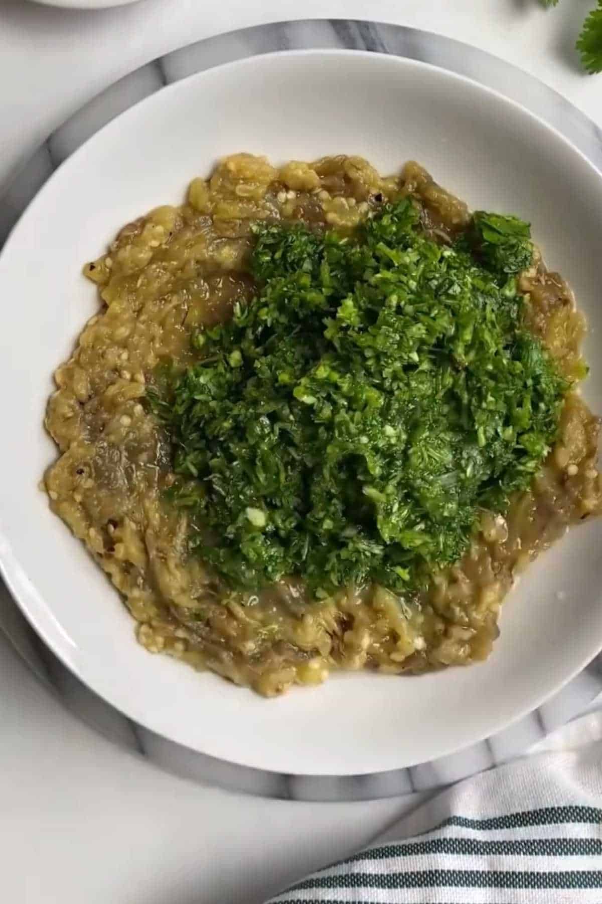 Green herb mixture and lemon jucie added to mashed eggplant. 