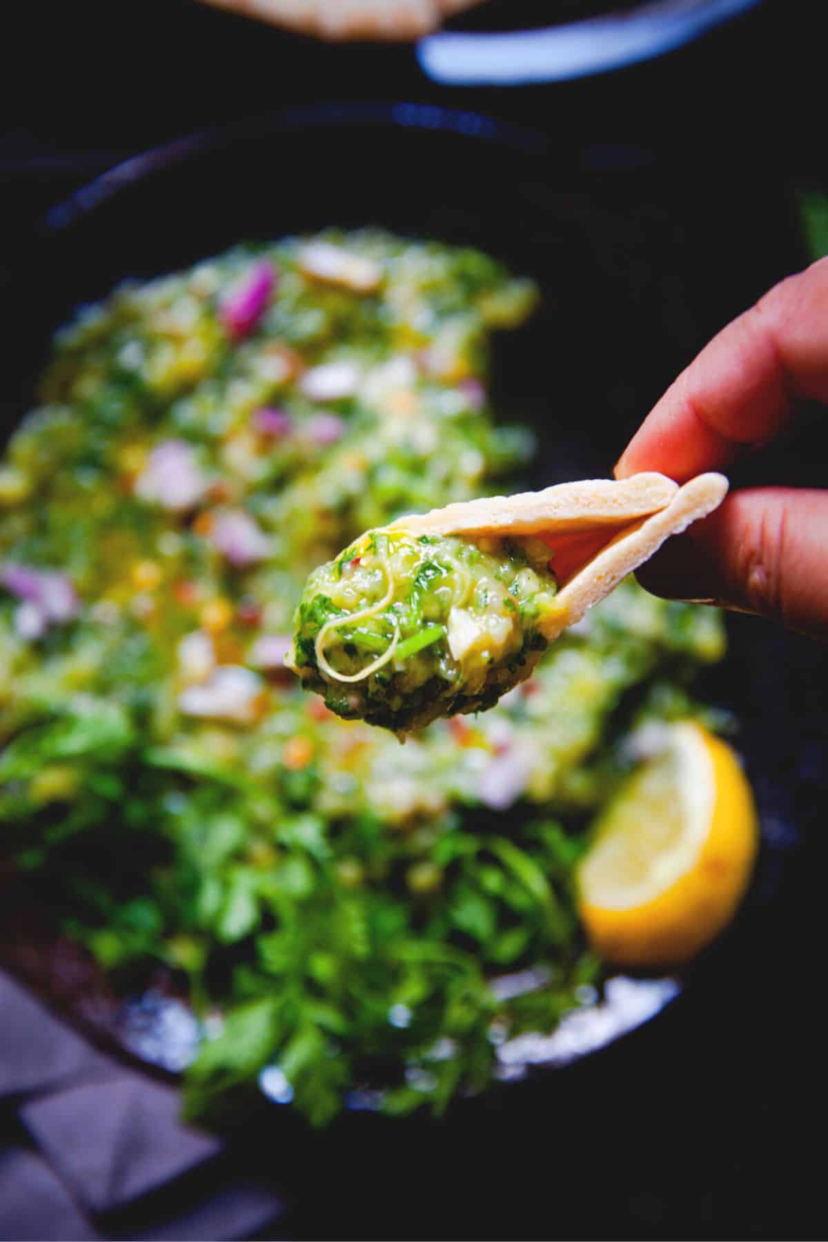 Green baingan bharta picked up with a small piece of naan. 