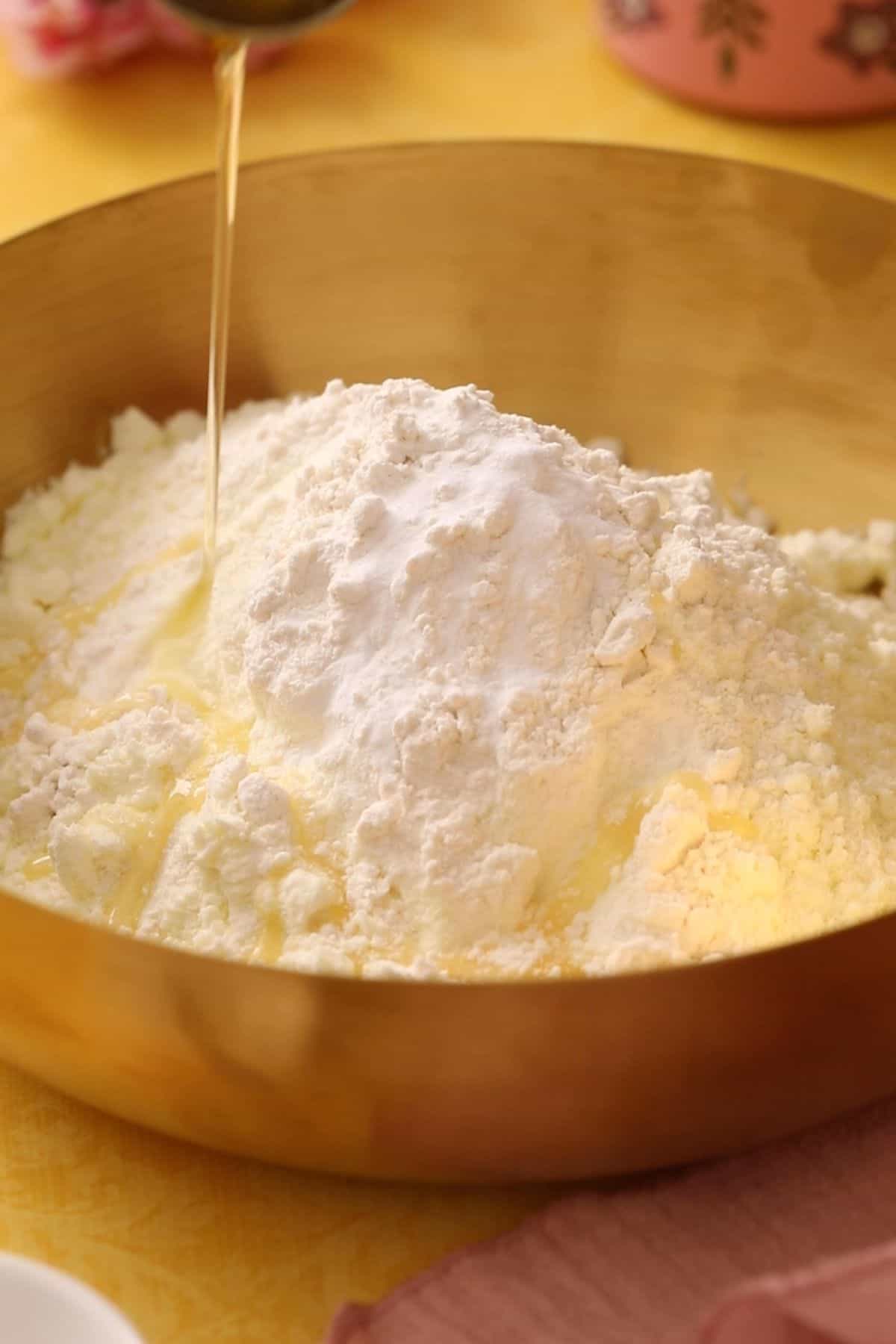 Dry ingredients with ghee being drizzled in a large gold bowl.
