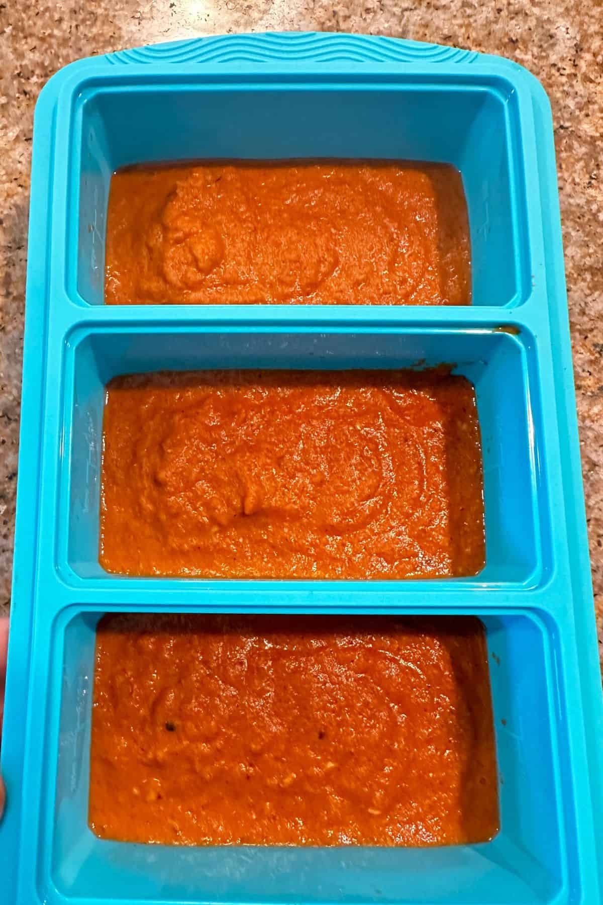 Indian curry sauce is portioned in blue silicone soup trays and is ready to freeze.