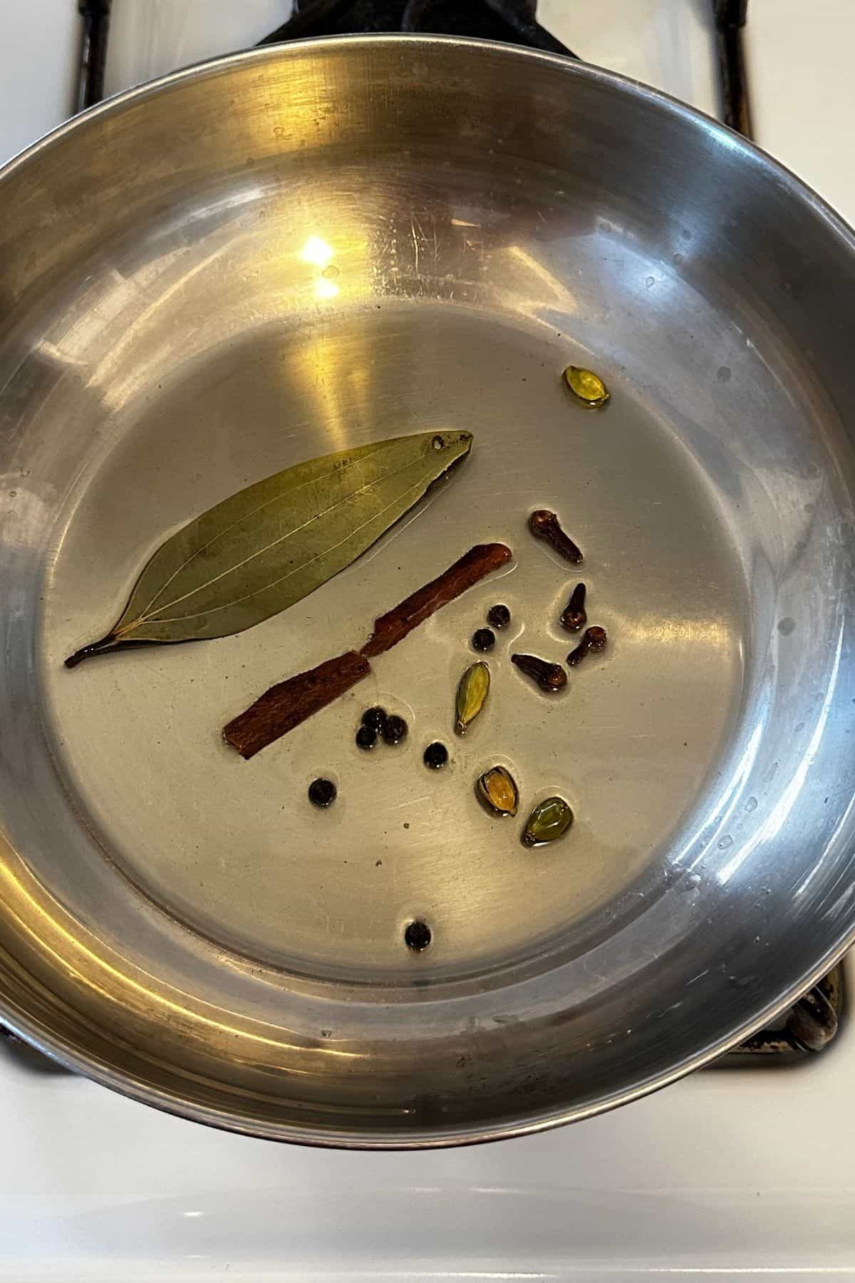 Hot oil is tempered with whole spices to make bhuna onion tomato masala. 