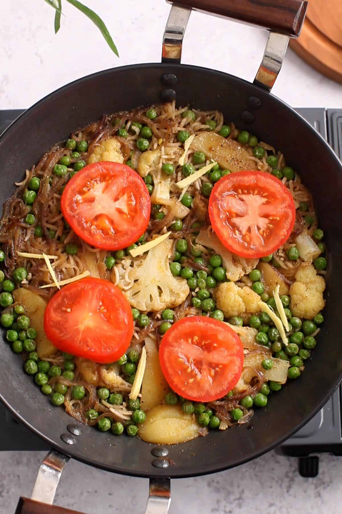 Cooked tahari is topped with tomato slices.