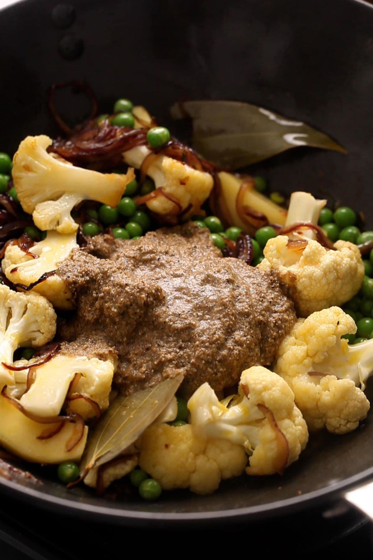 Vegetables and ground spice paste is added to the fried onions.