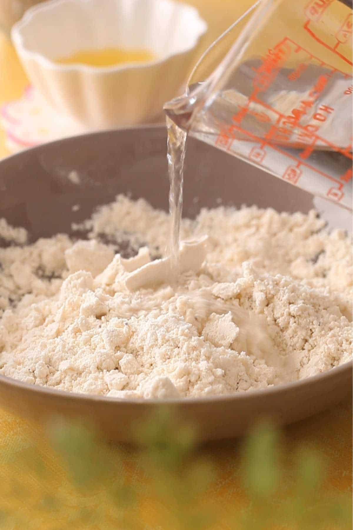 Adding water to flour to make dough.