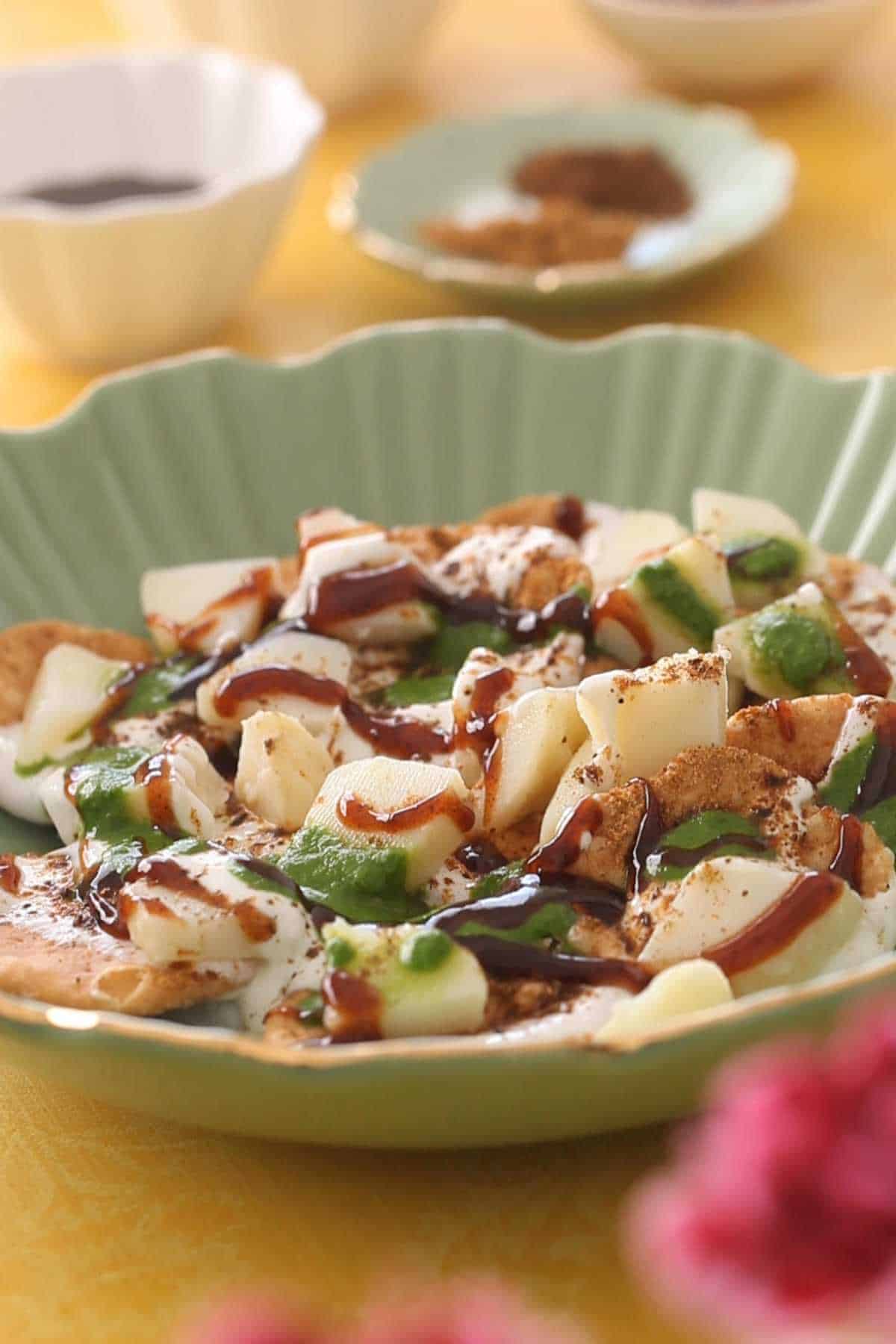 Adding green chutney and tamarind chutney to papdi chaat.