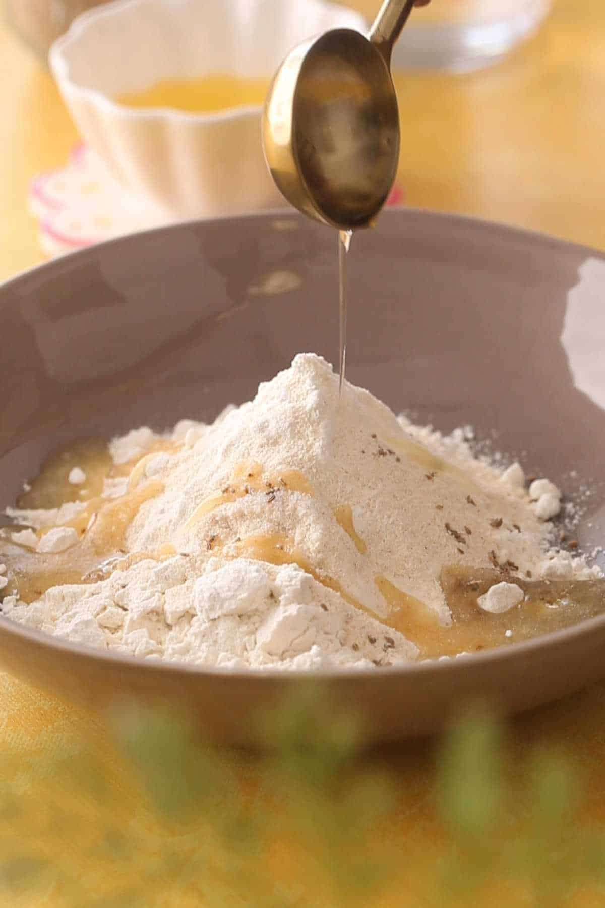 Adding melted ghee to papri dough.