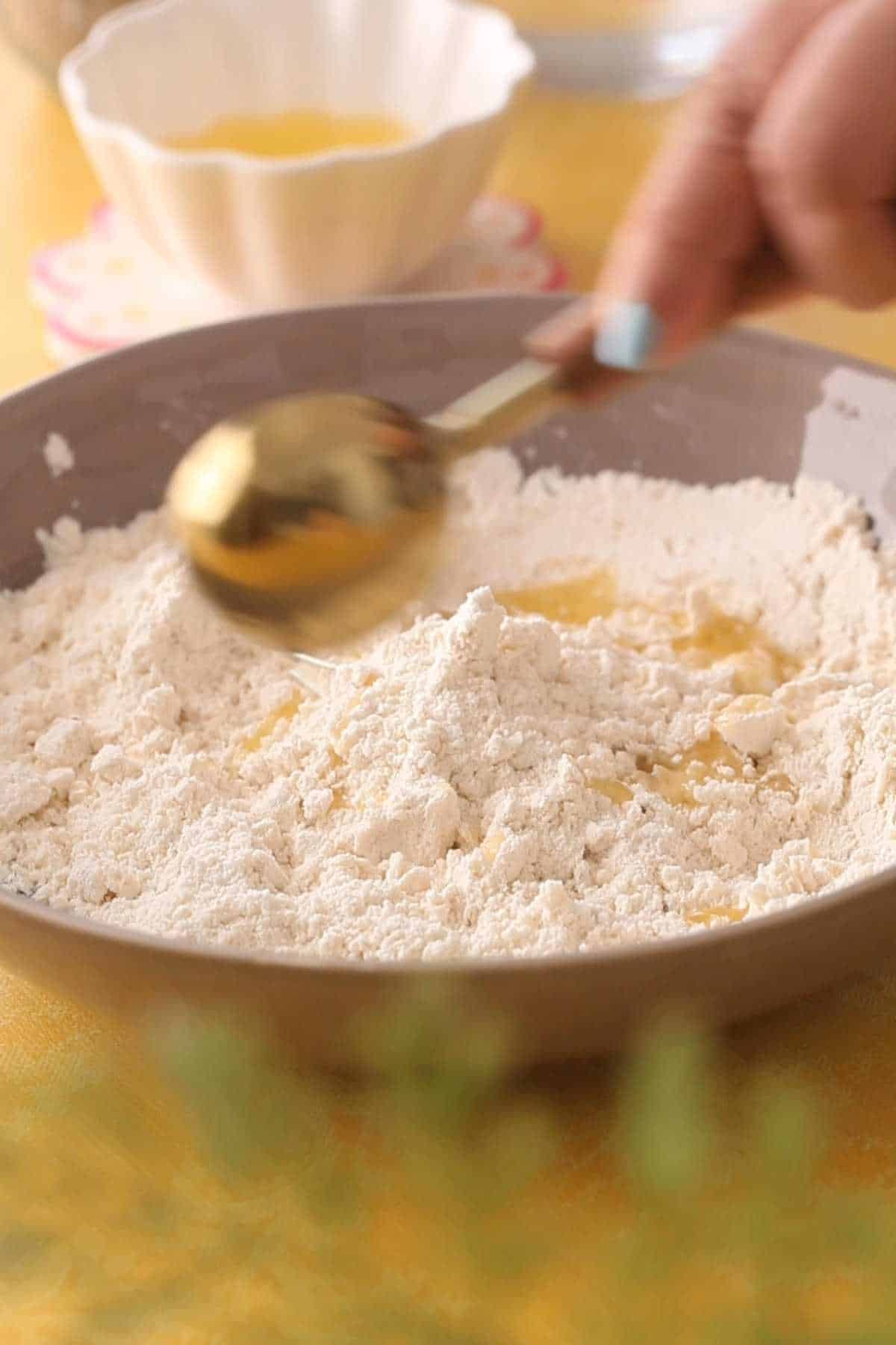 Adding more melted ghee to the flour for papri chaat.