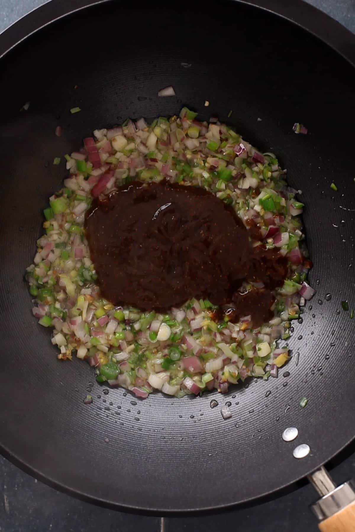 Adding condiment base to the wok.