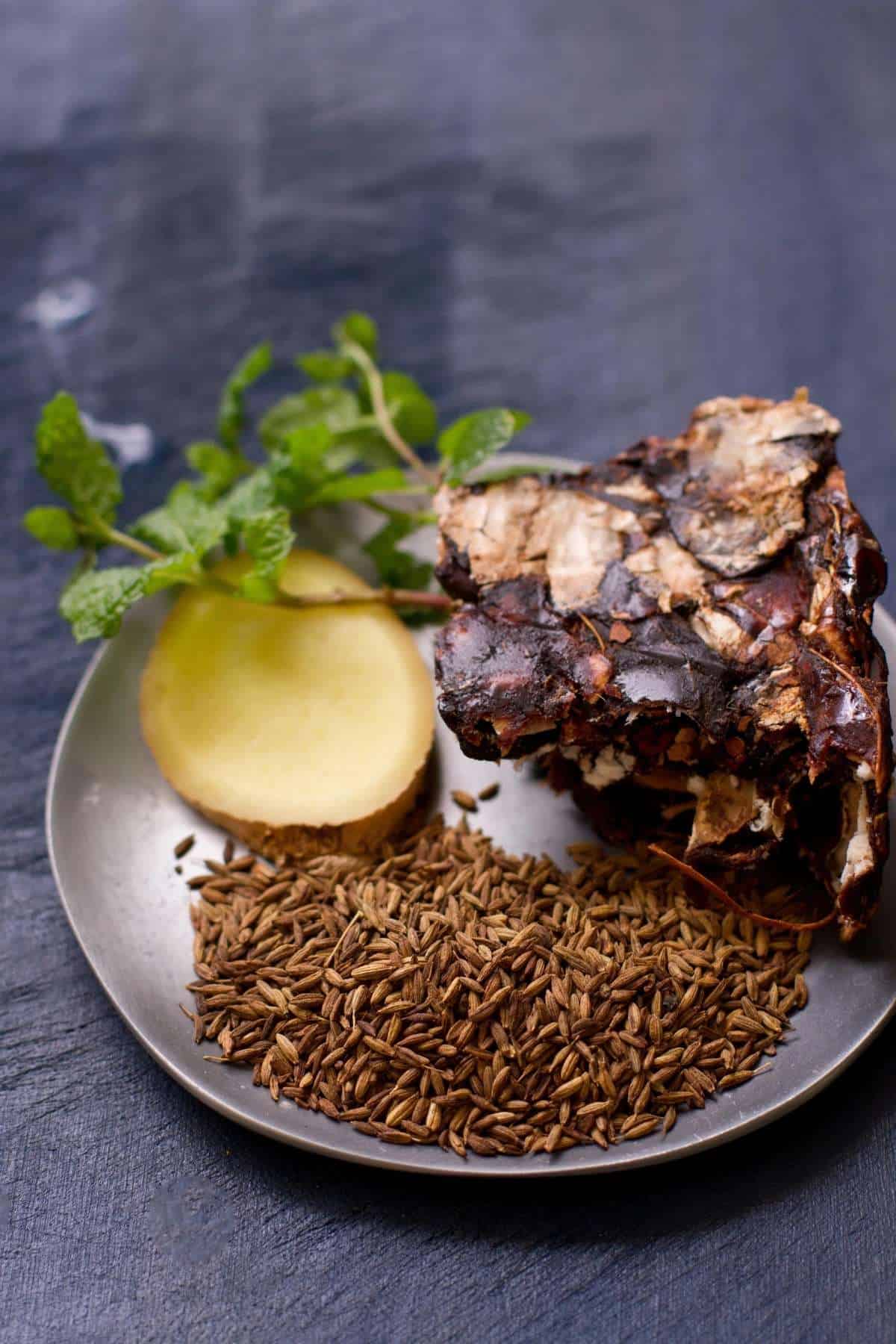 Ingredients needed for making indian tamarind and cumin summer cooler placed in a pewter plate. 