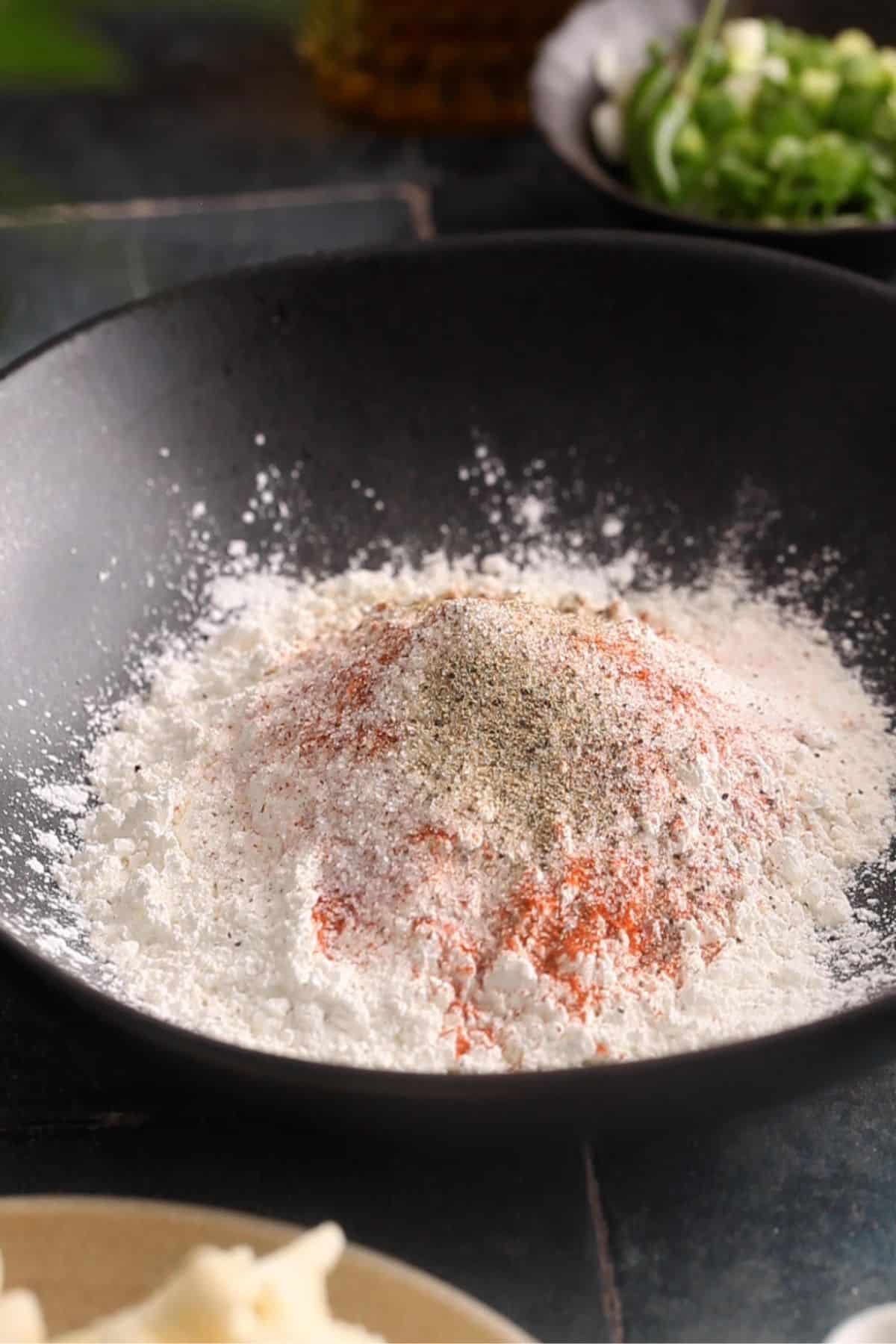 Ingredients for flour batter in a black bowl.
