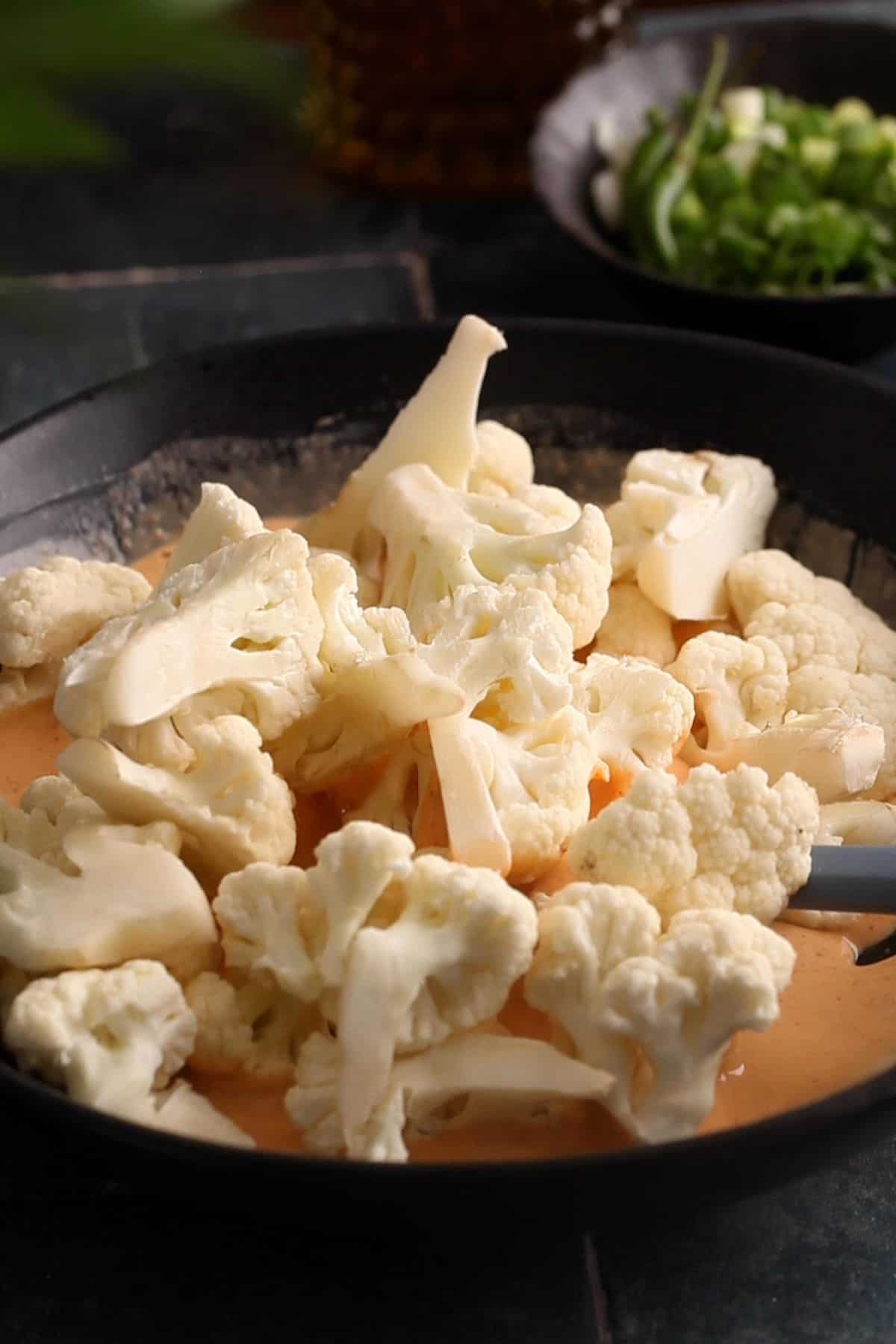 Adding cauliflower florets to the batter.