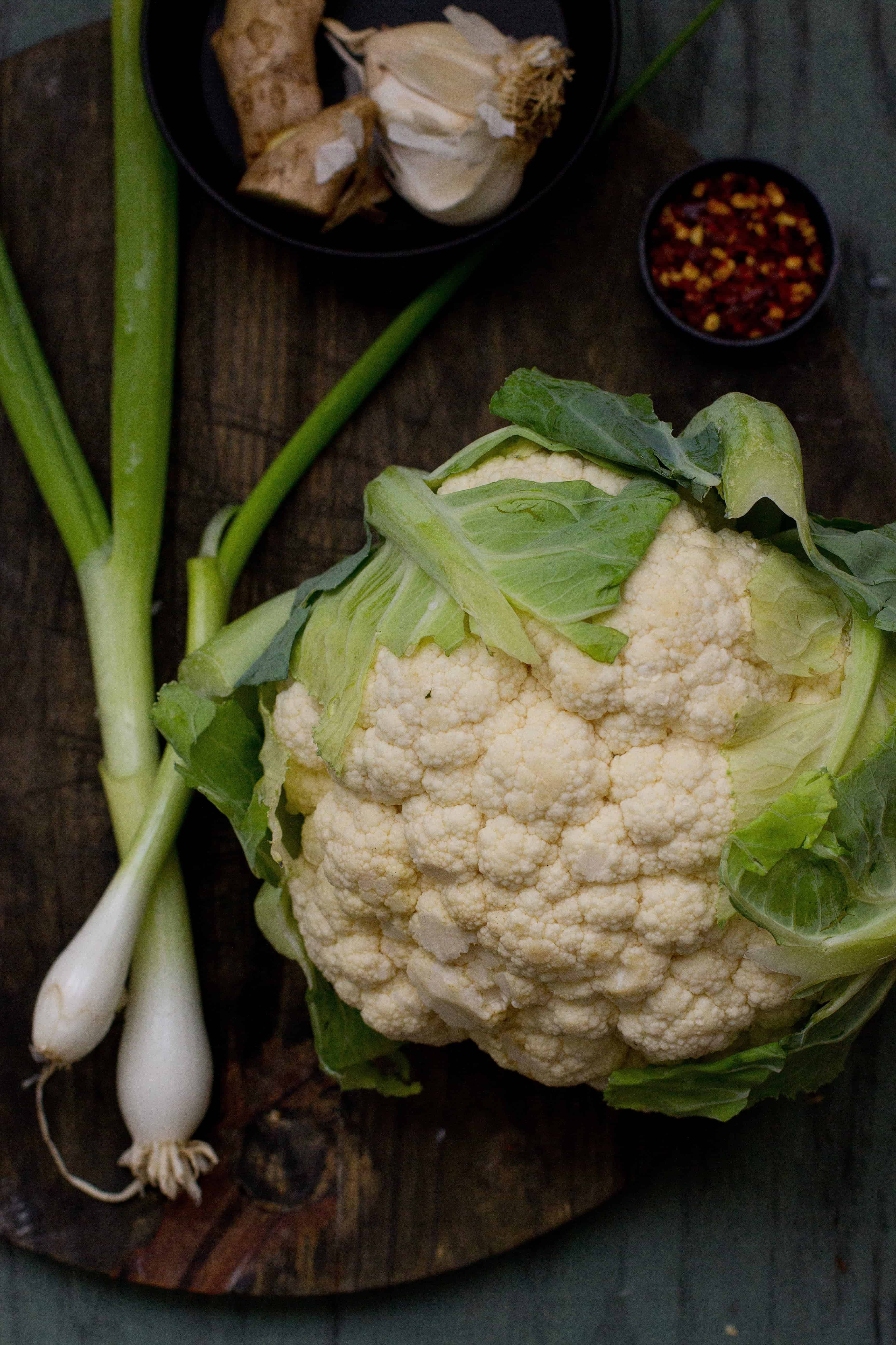 Ingredients, Gobi (Cauliflower) Manchurian via Sinfully Spicy Cauliflower head on a wooden board.