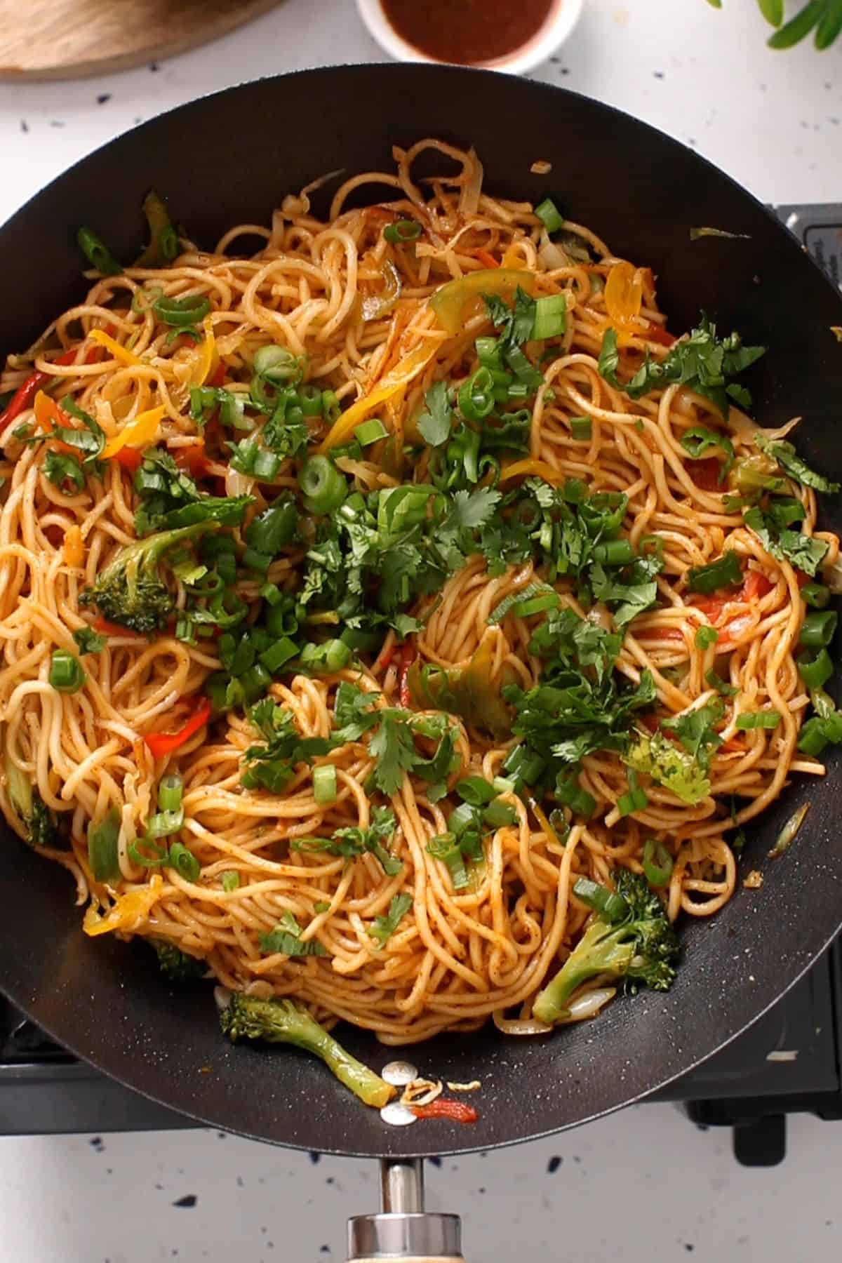 Veg hakka noodles are ready and topped with fresh chopped green herbs.