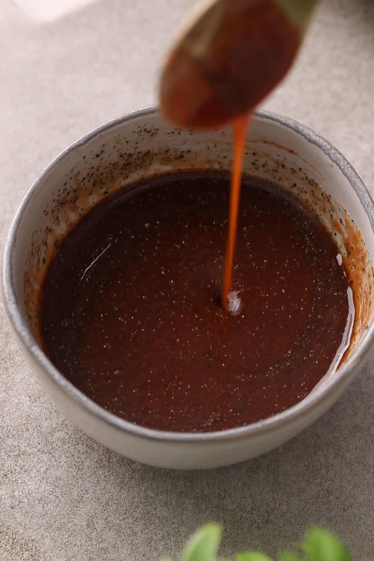 The stir fry sauce for noodles is mixed in a grey bowl.