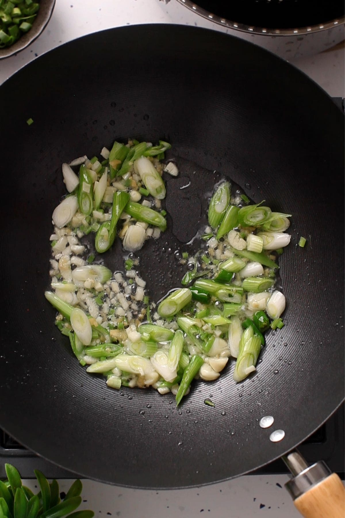 Aromatics are sizzling in oil in a chinese wok.