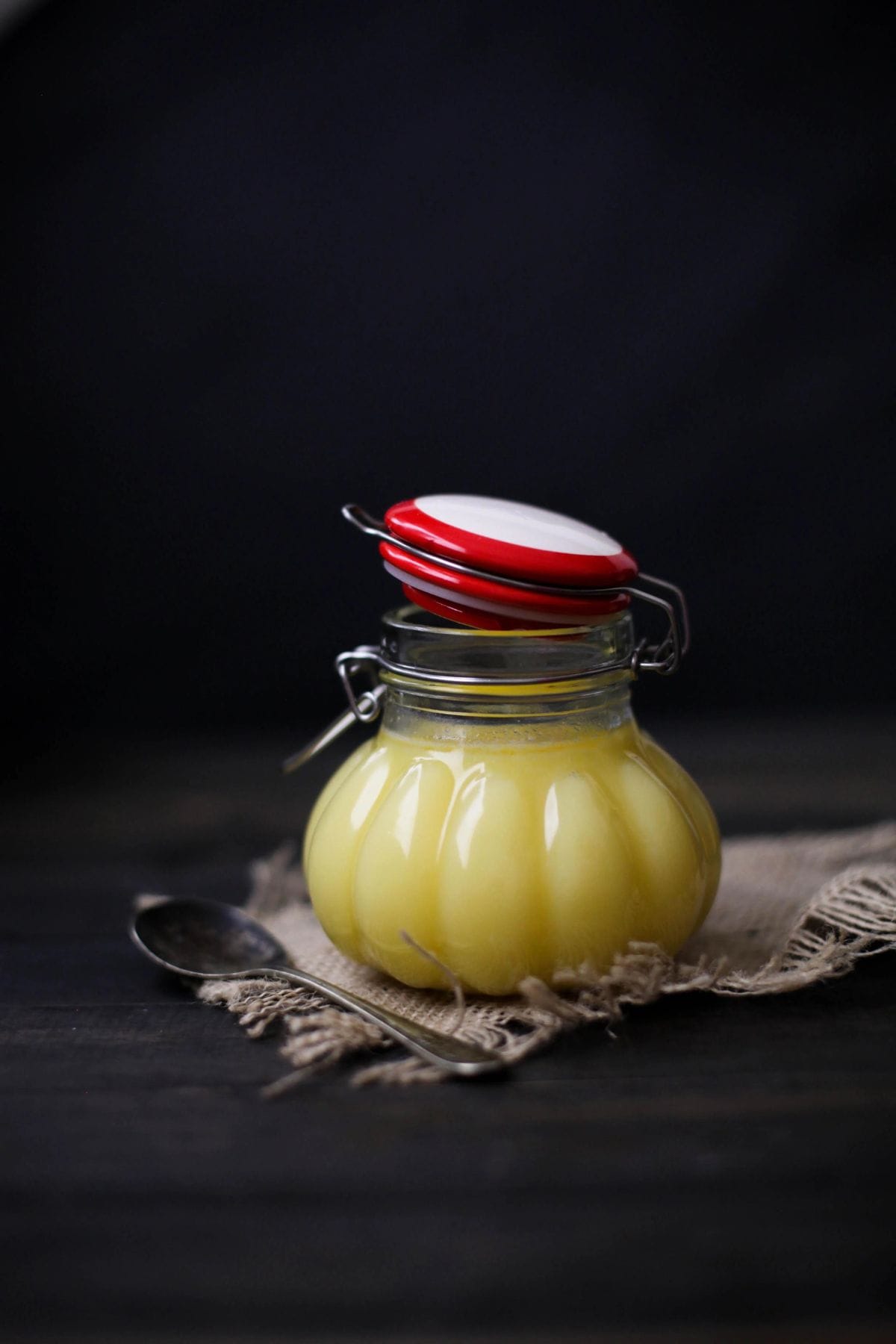 A jar of homemade ghee on a black background.