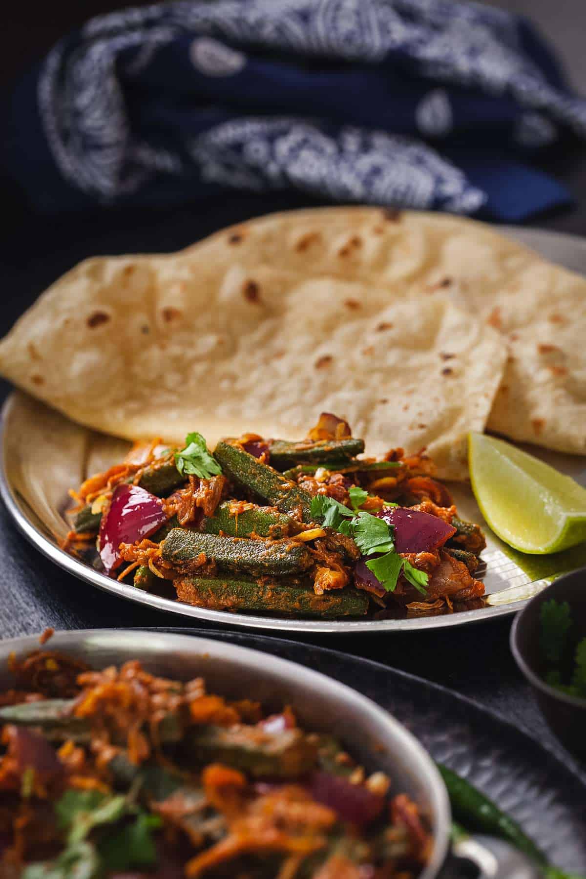 Side view of bhindi Dp pyaza served with rotis in a stain less steel plate. 