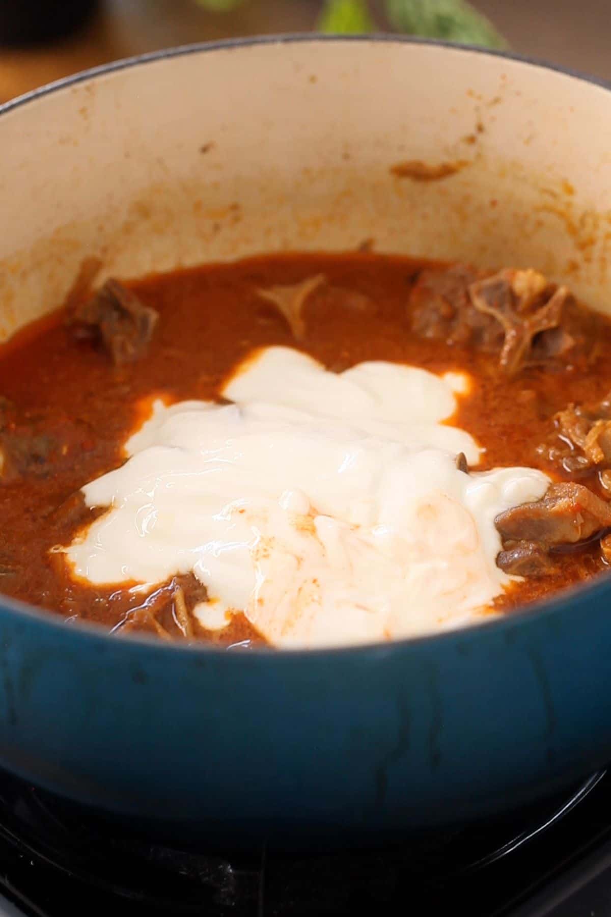 Whisked yogurt is added to the cooking pot.