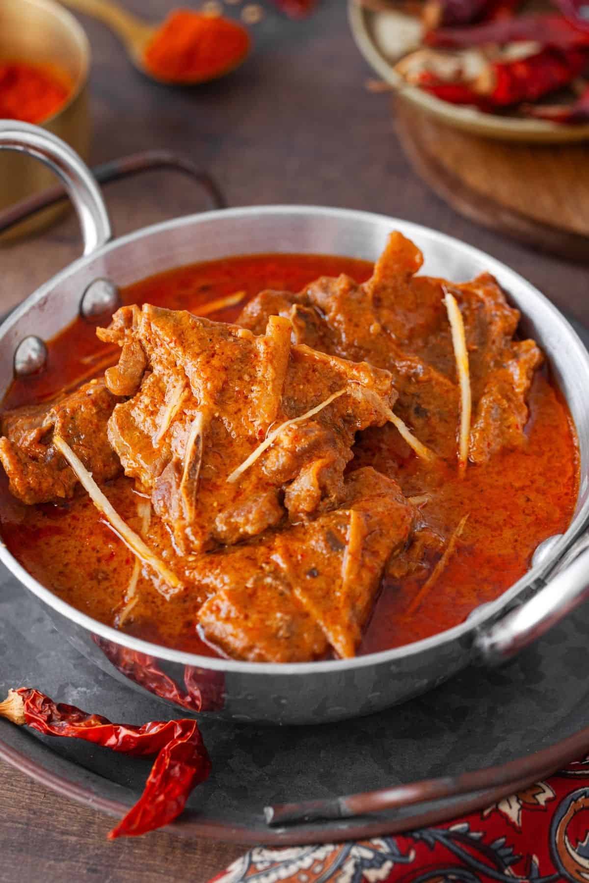 Angle view of laal maas in an aluminum kadai. 