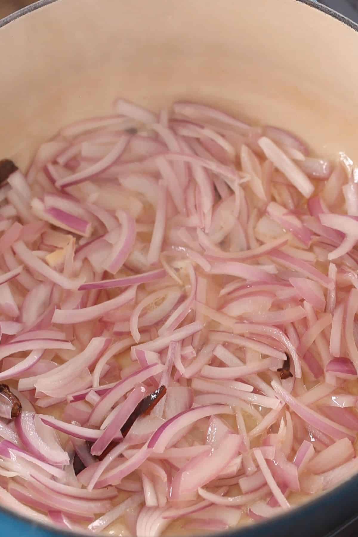 Sliced onions added to the cooking pot.