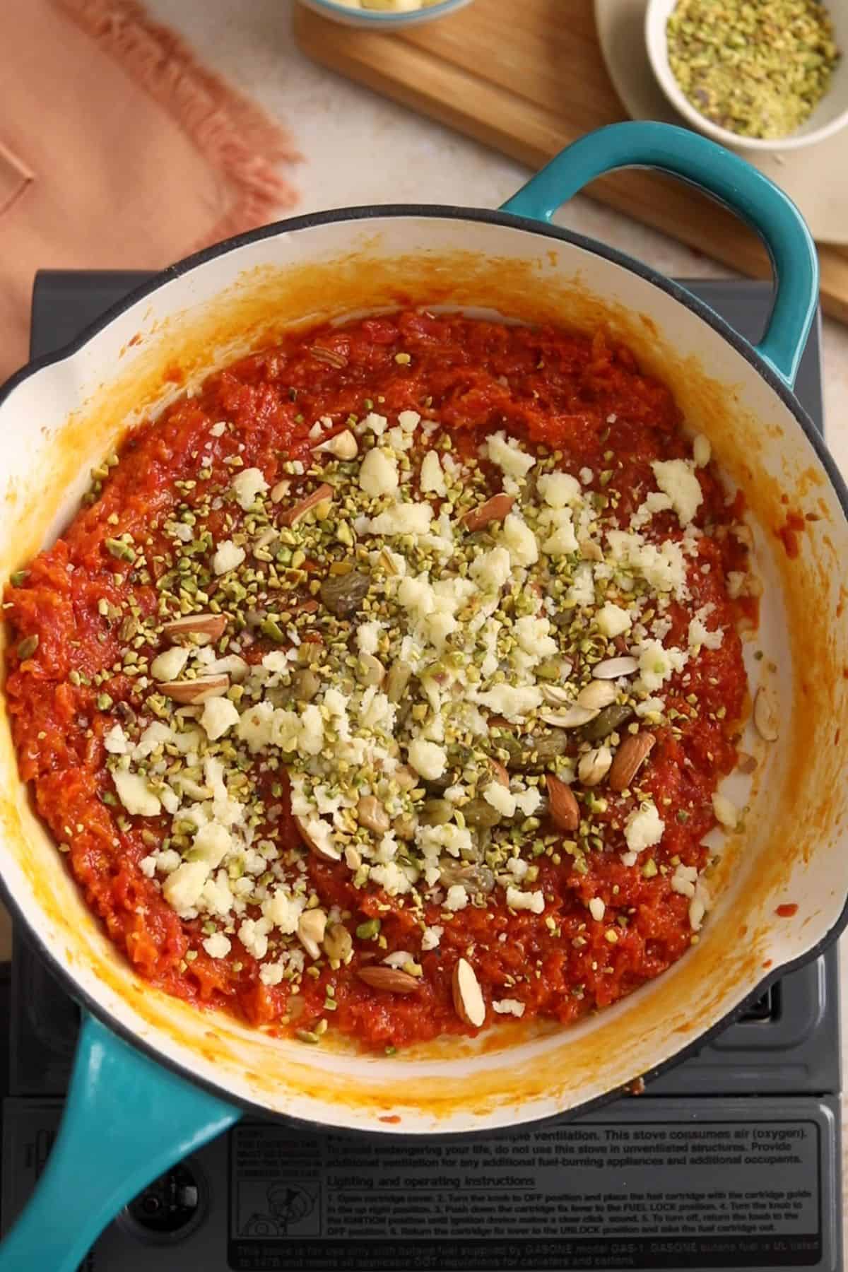 Chopped nuts, raisins and crumbled khoyaias added to carrot halwa. 