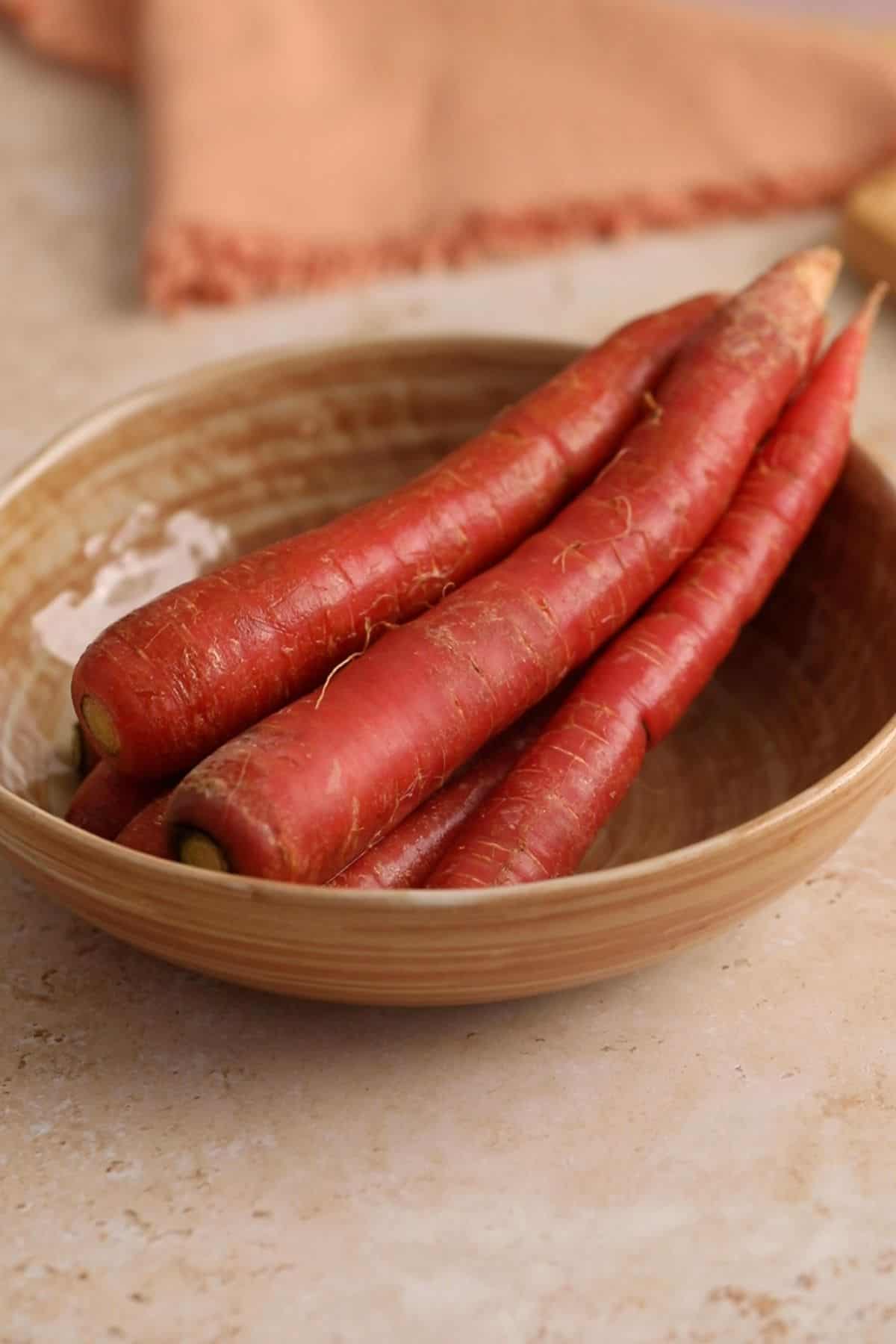 Red carrots placed in a brown beige bowl. 