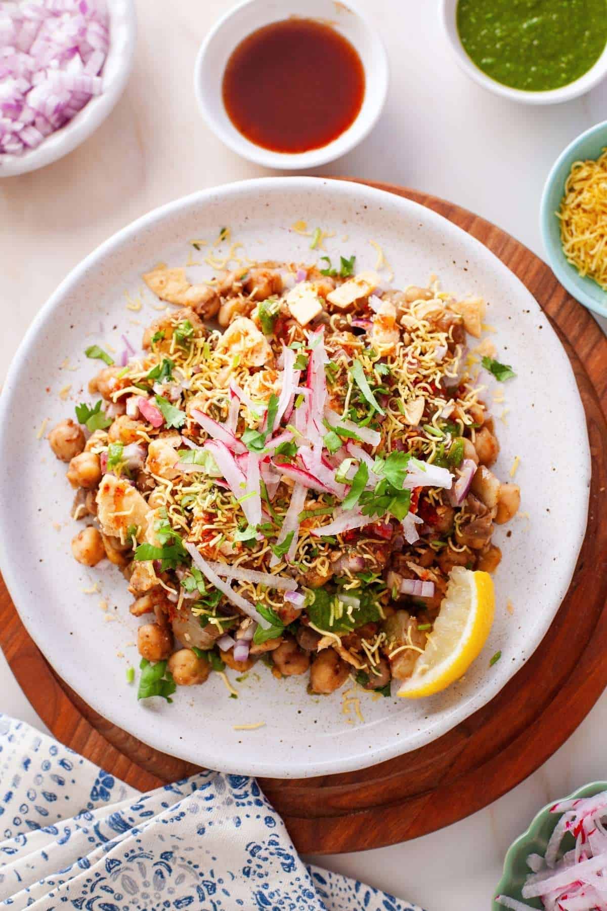 Chickpeas and potatoes chaat on a marbel background with spices and chutneys. 