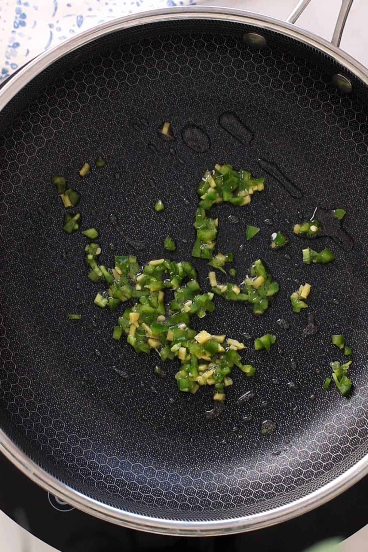 Frying green chillies & ginger in oil.