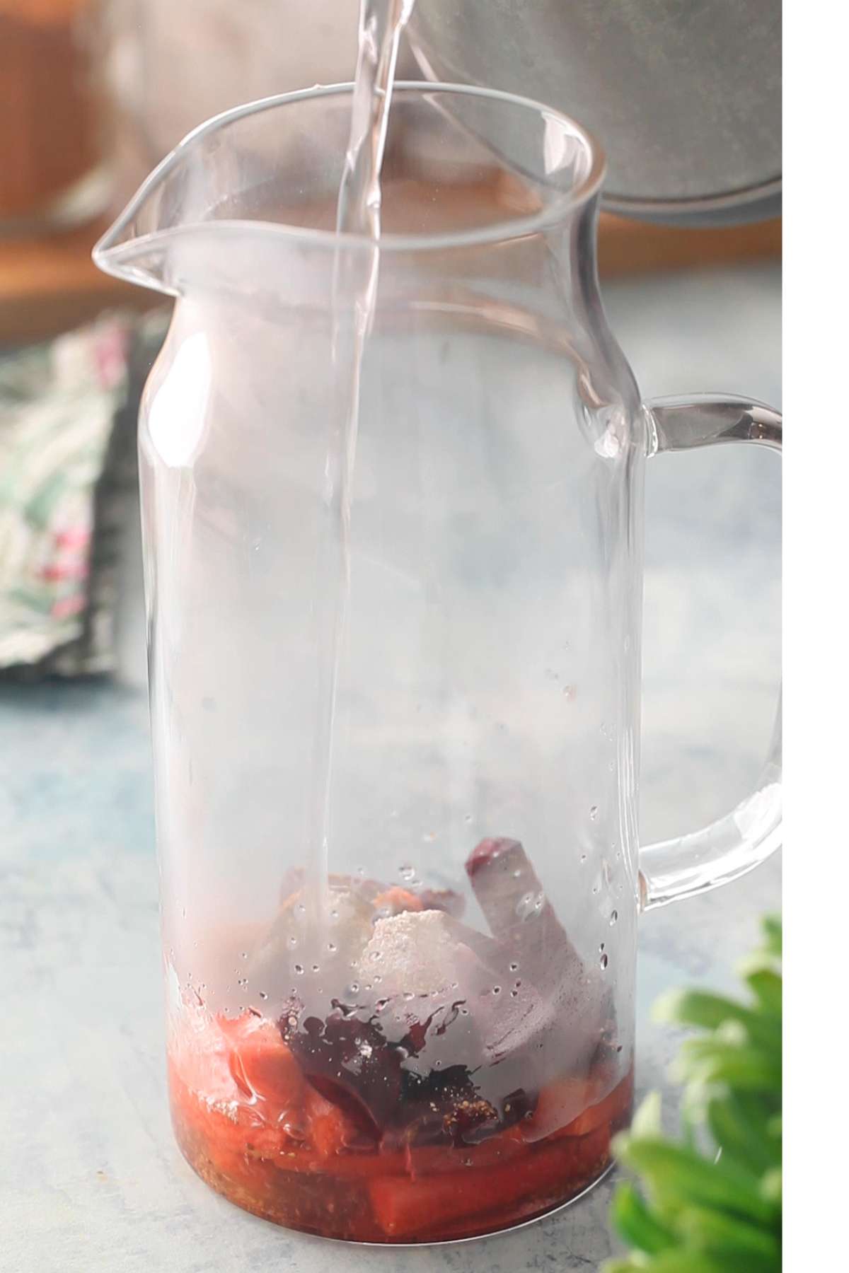 Adding hot water to the carrots, beetroot and spices.