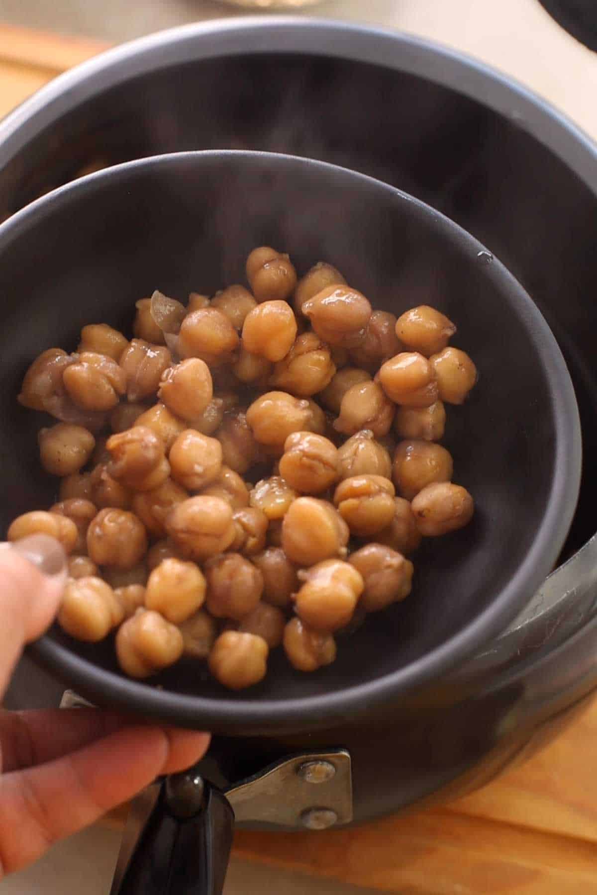 A small portion of boiled chikpeas in a black bowl.