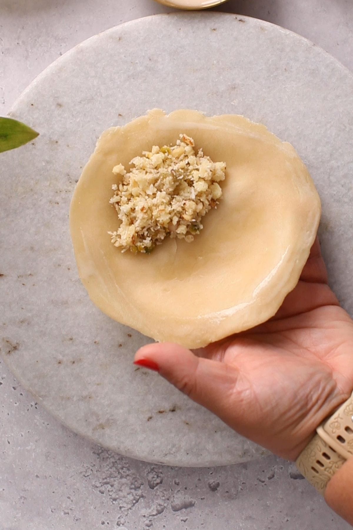 Rolled gujiya dough is put on a mould and filled with mawa filling.