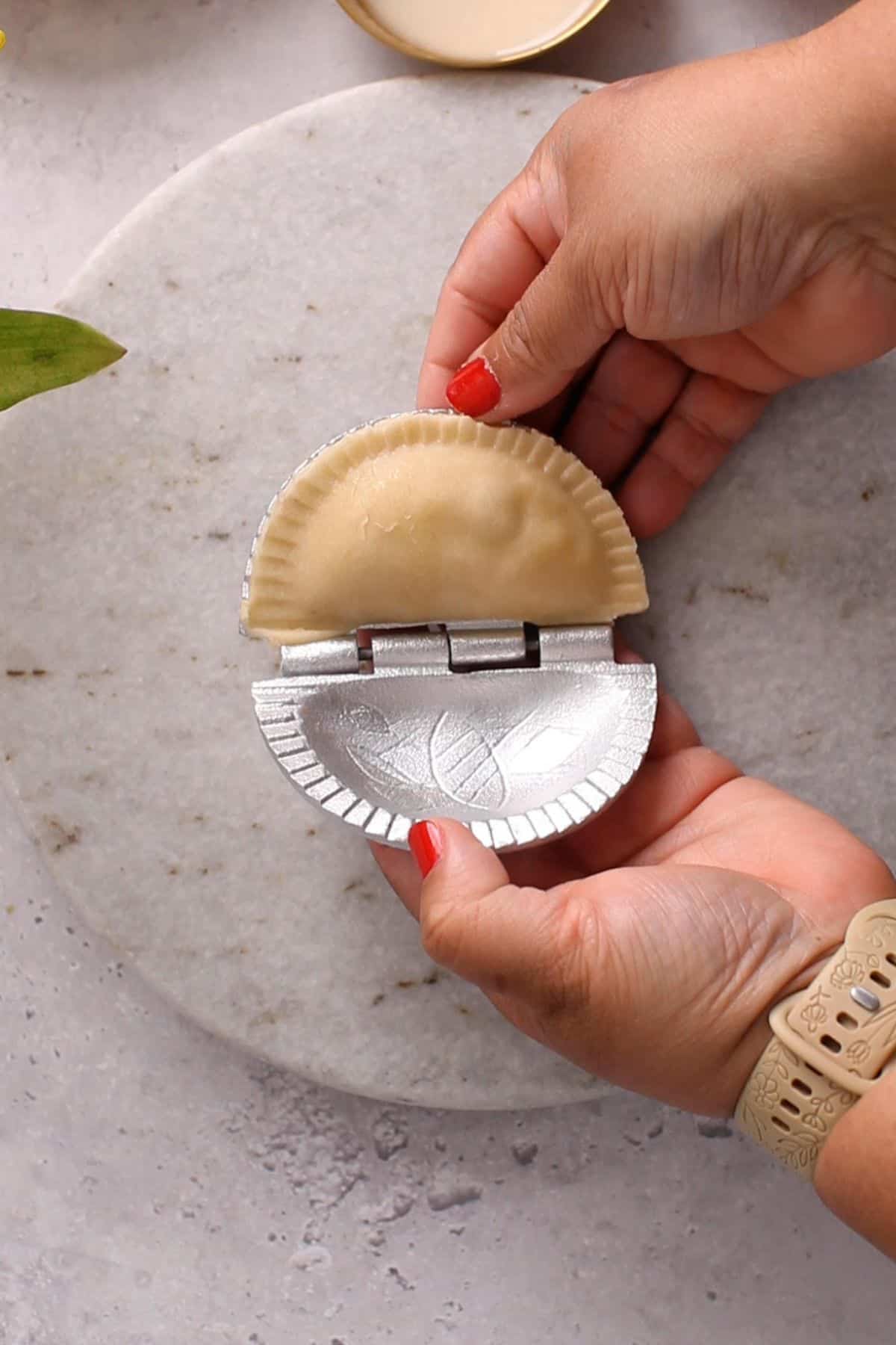 Gujiya shaped in a mould. 