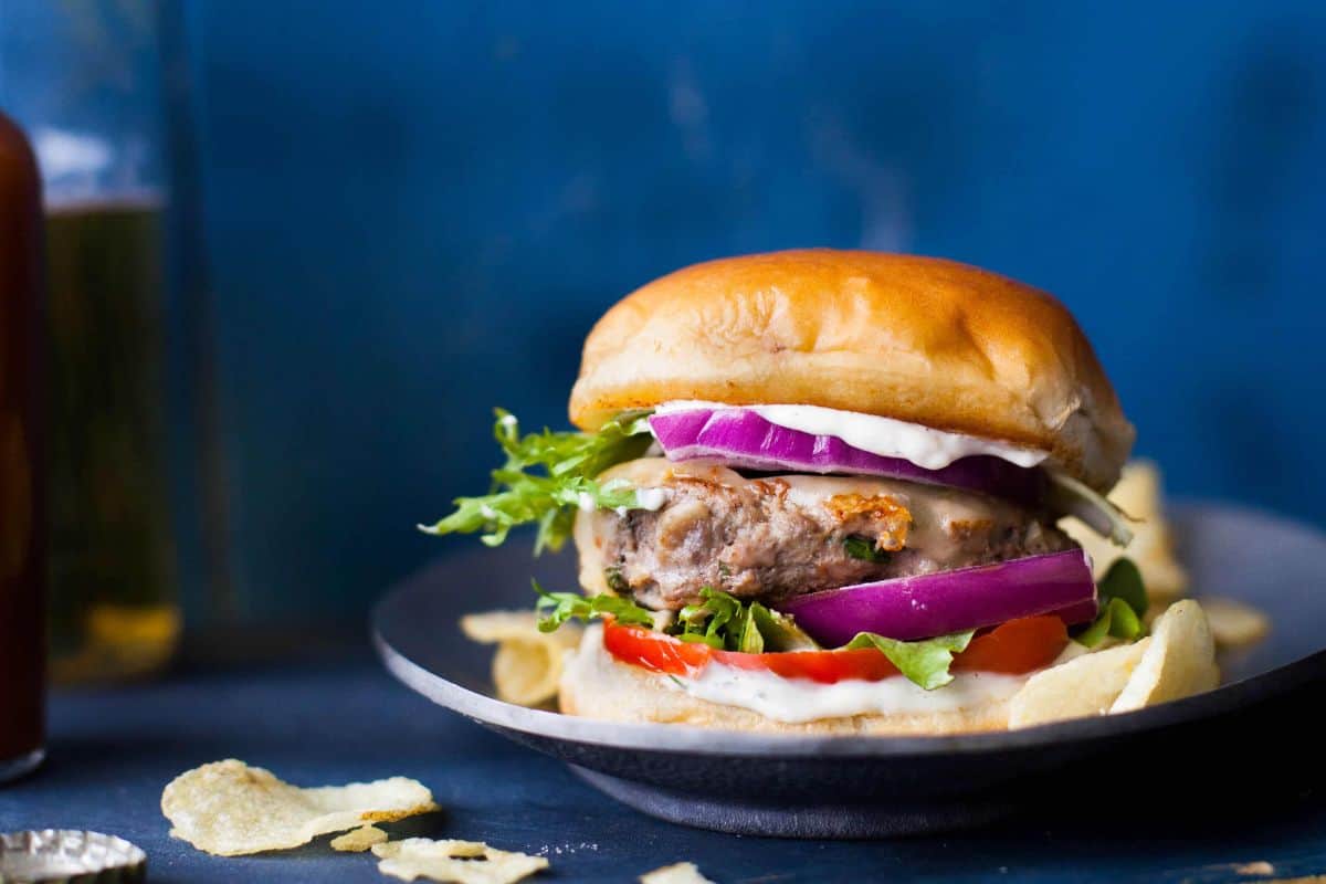 Indian style lamb burger placed on a steel plate with chips.