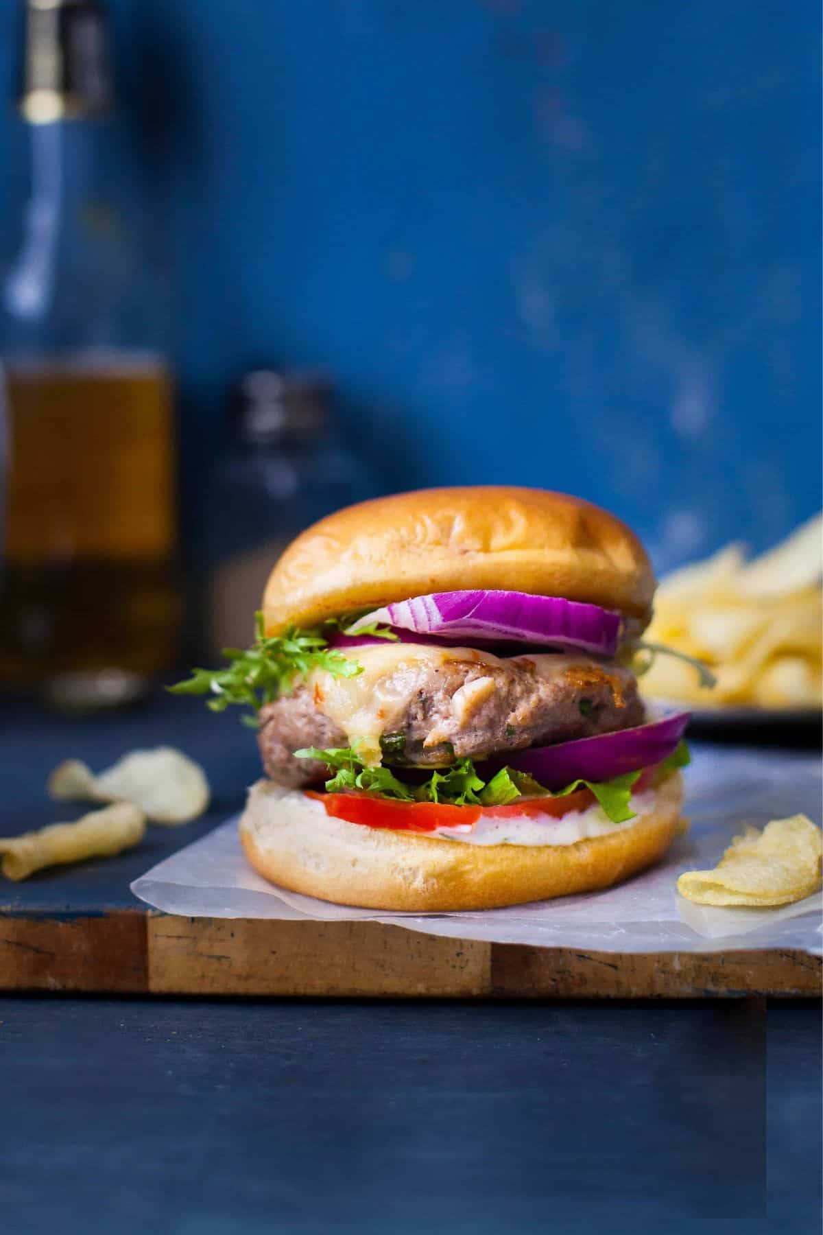 Lamb buger with melted cheese with a beer in the background.