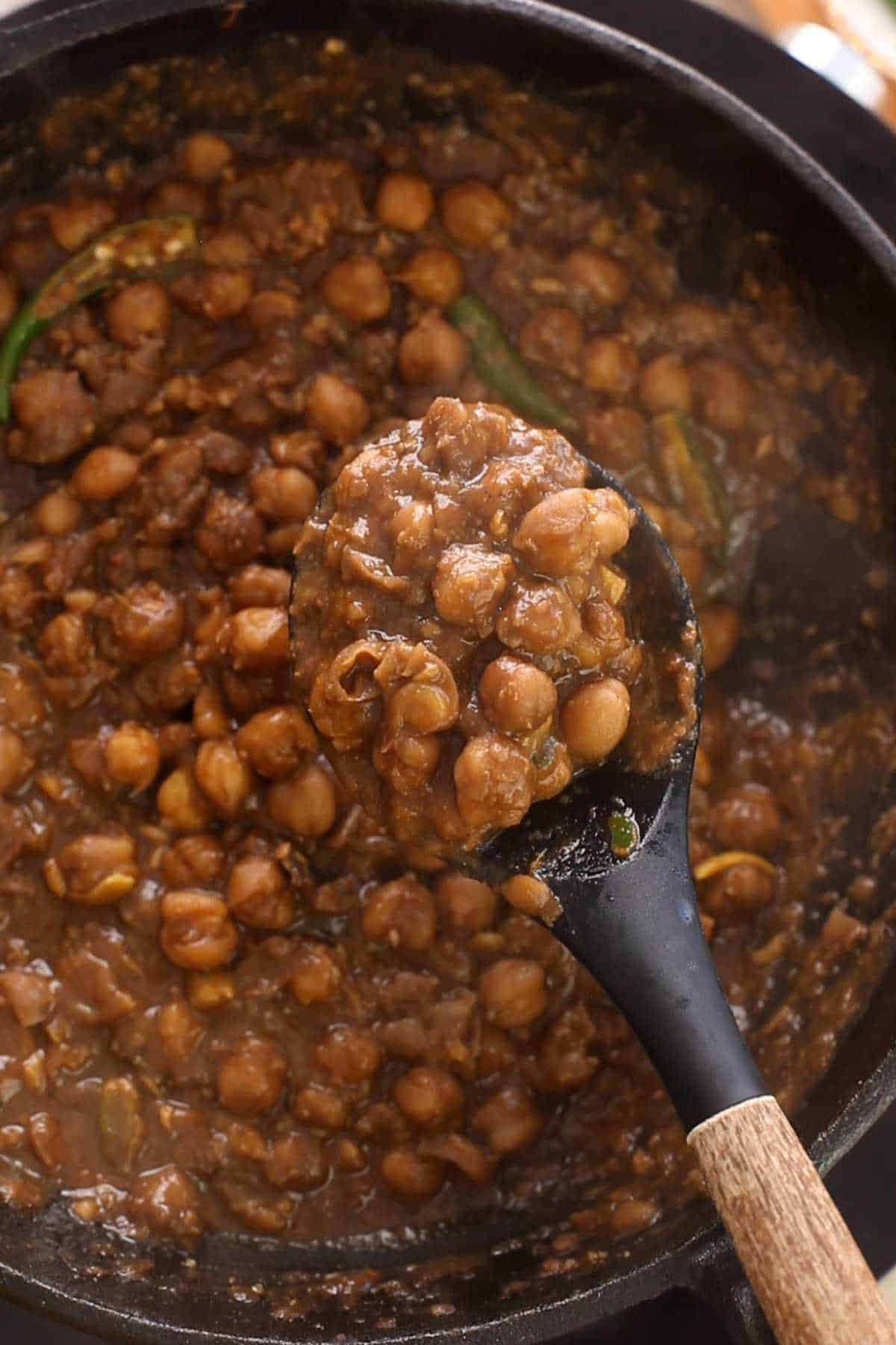 Pindi chole scopped in a black spoon.