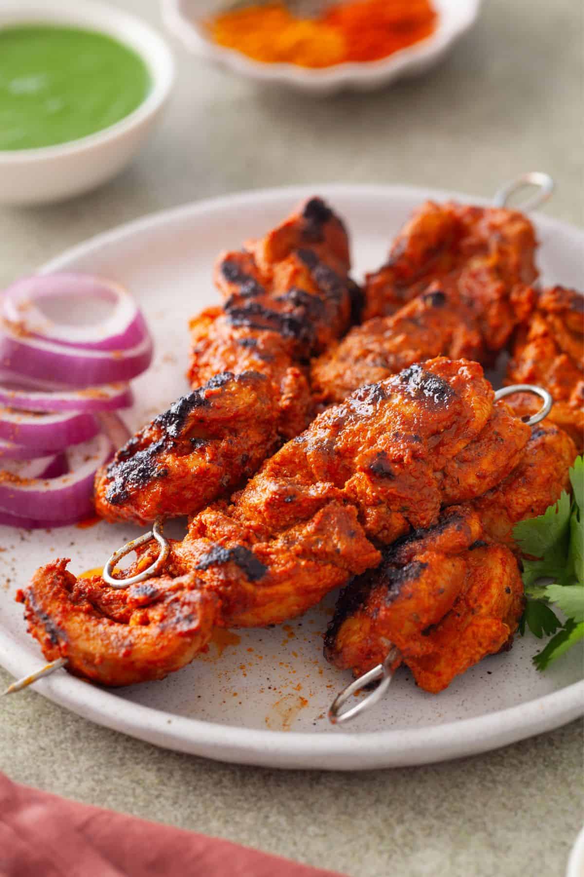 Side view of chicken tikka on a white plate.
