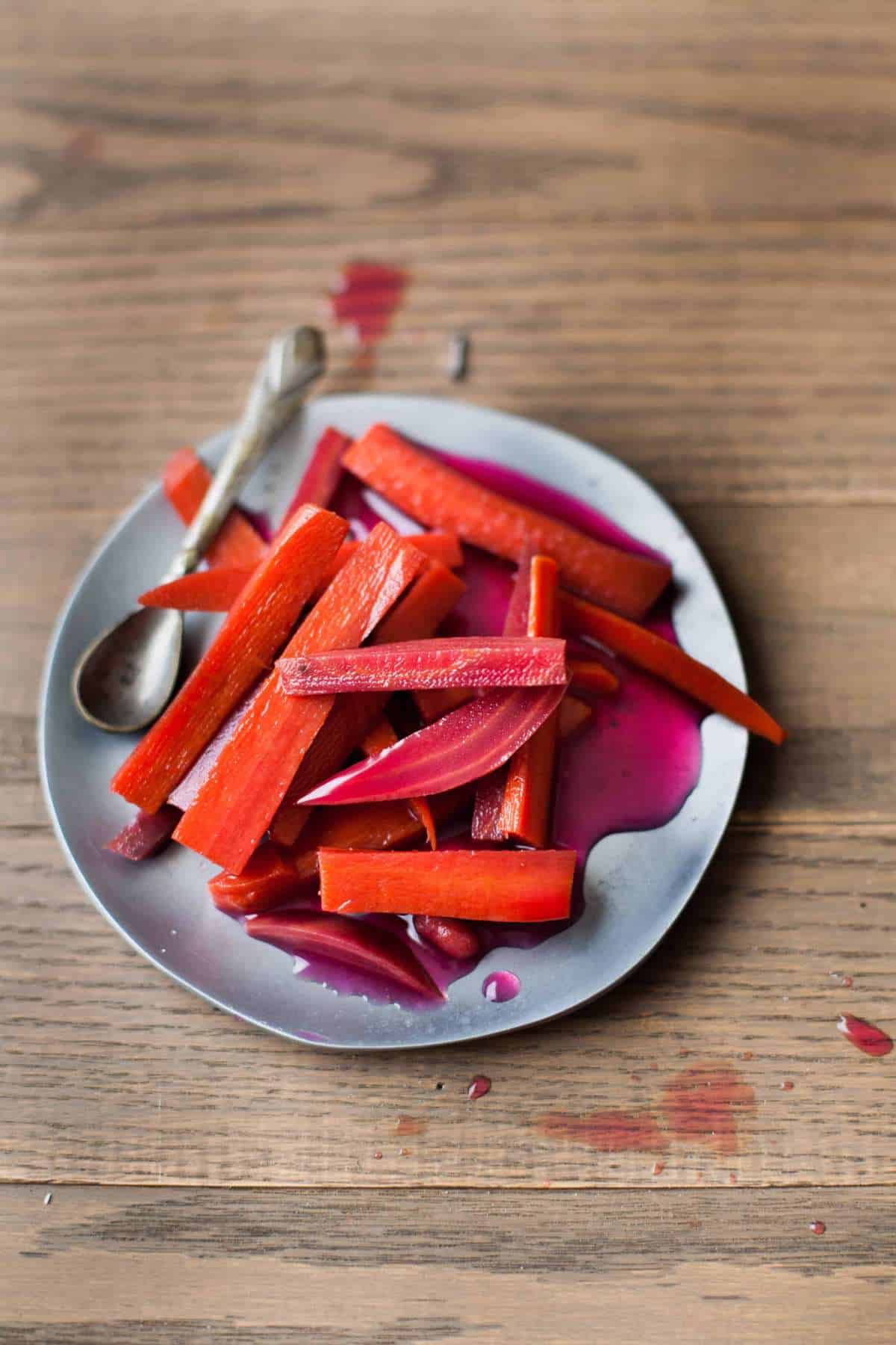 Pickled carrots and beetroot sticks placed on a metal plate.