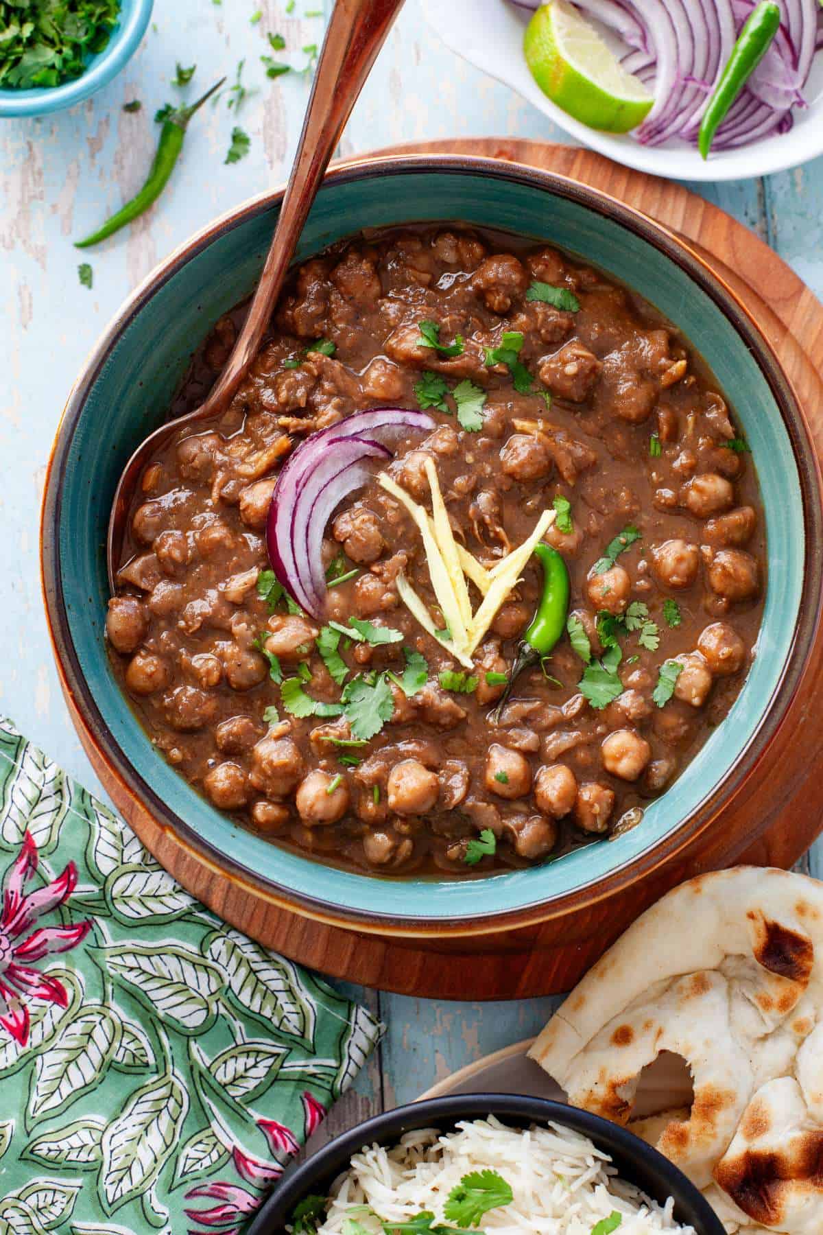 Pindi Chana in a blue bowl topped with ginger julinnes and onions.