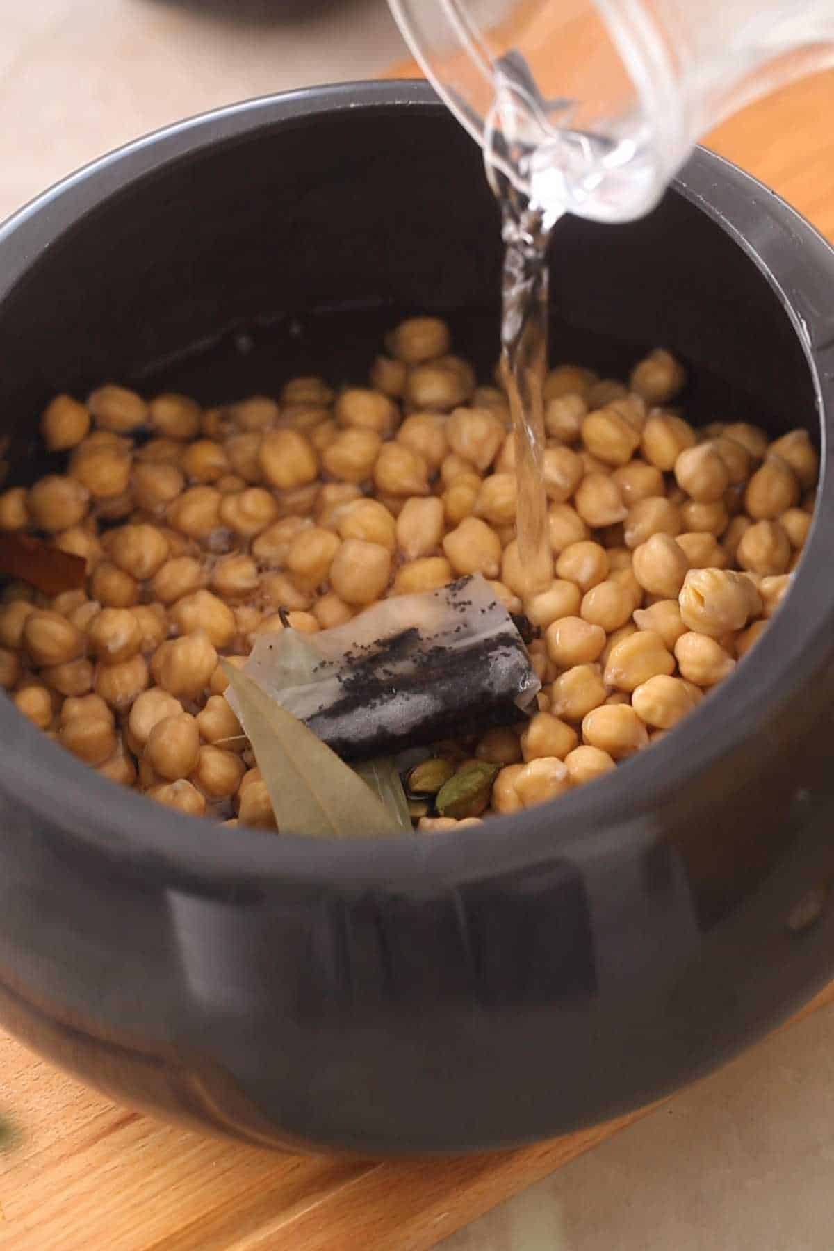 Adding water for pressure cooking the white chickpeas.