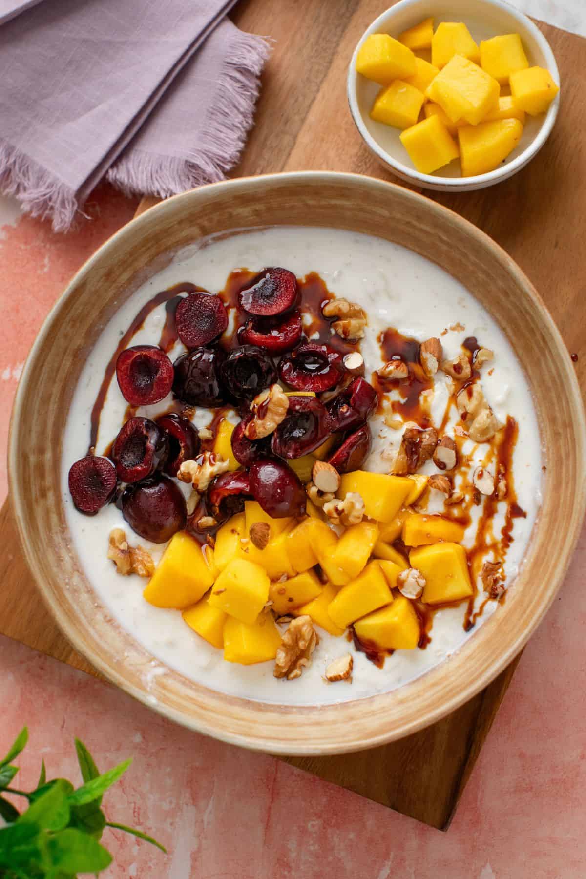Top image of sweet dahi choora with mango in a small bowl on side.