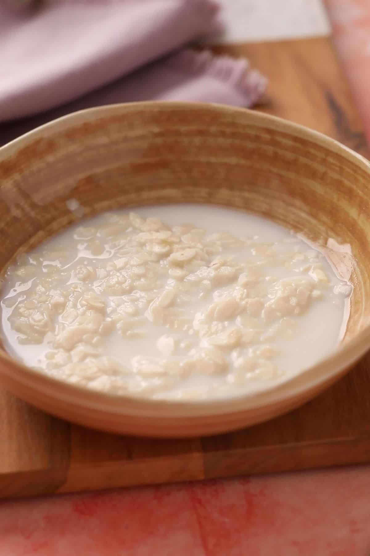 Poha is soaked in milk in a beige bowl