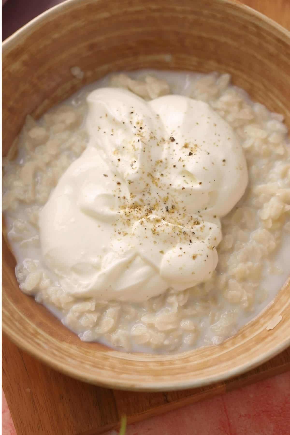 Soaked poha is topped with ypgurt and cardamom powder.