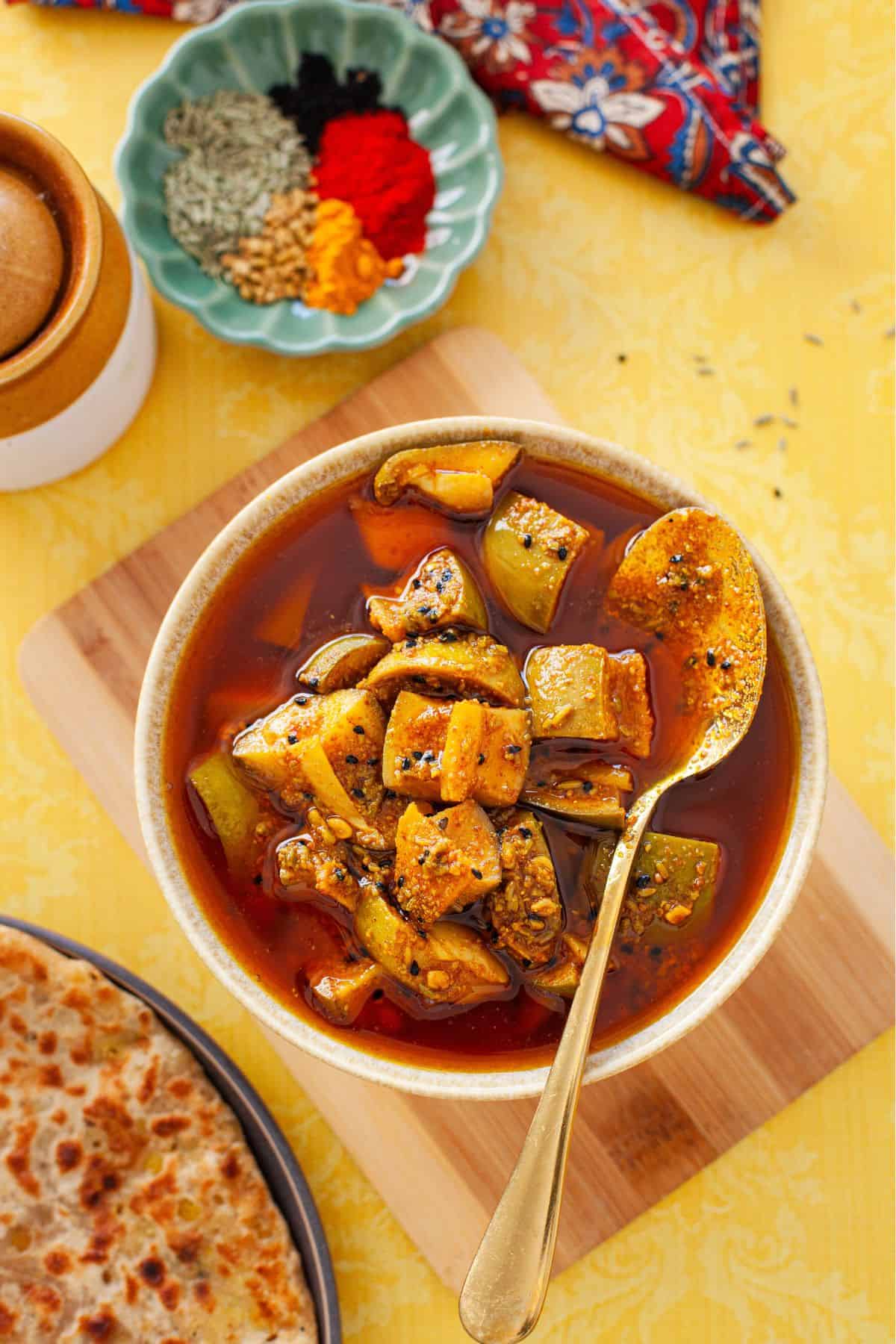Mango Pickle in a brown bowl with a gold spoon.