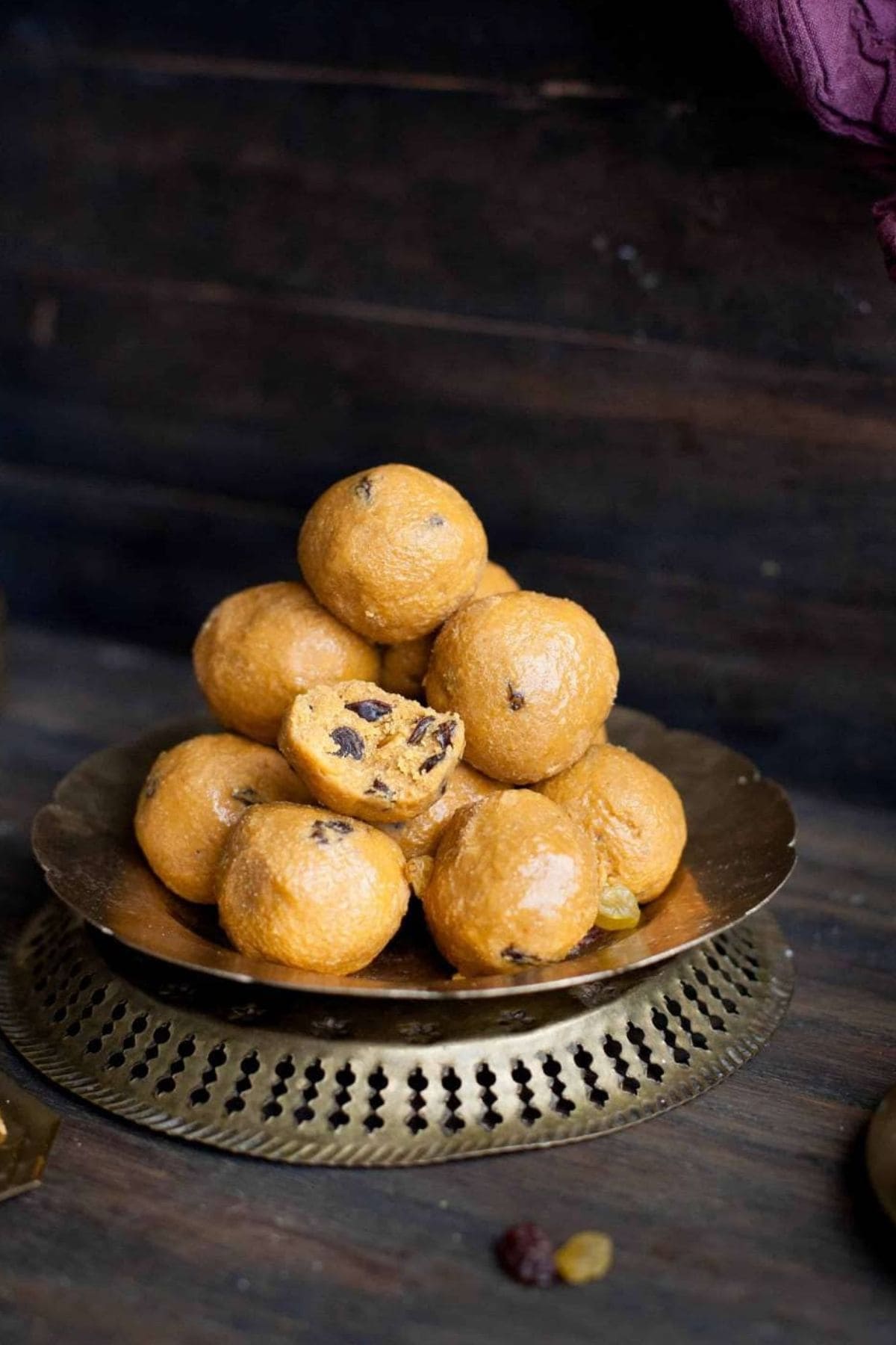 Besan ladoo stacked on an antique brass plate.