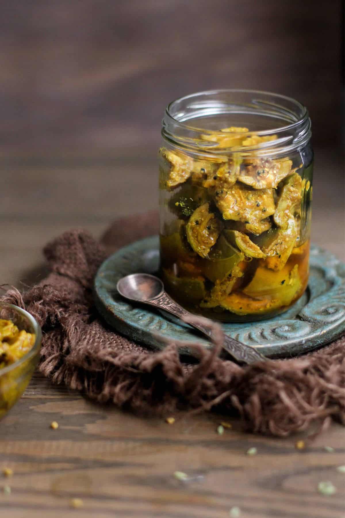 Front shot of Mango pickle in a glass jar with copper spoon.