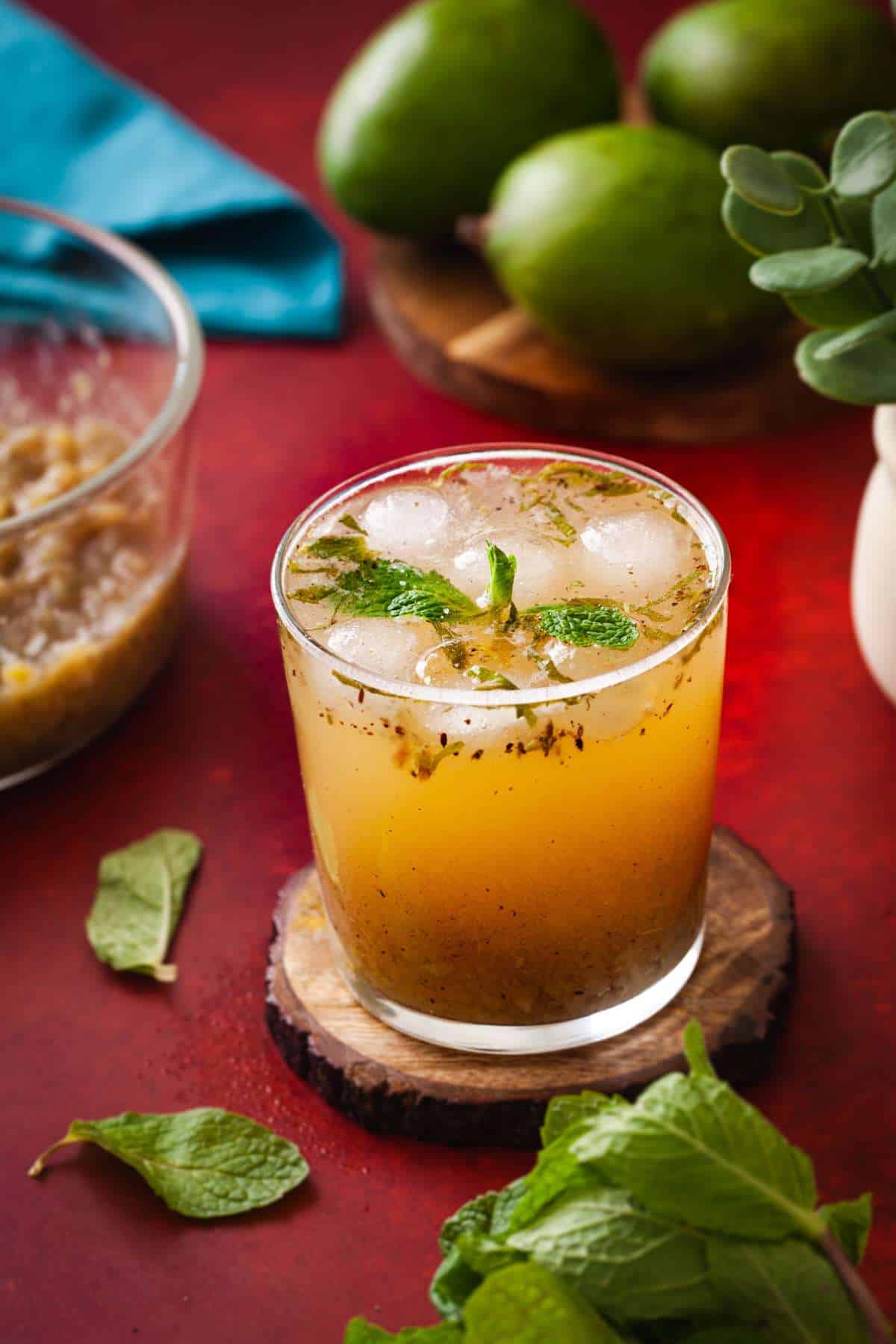 A chilled glass of aam panna, an indian summer cooler made with unripe green mangoes, spices and sugar placed on a brick red background.