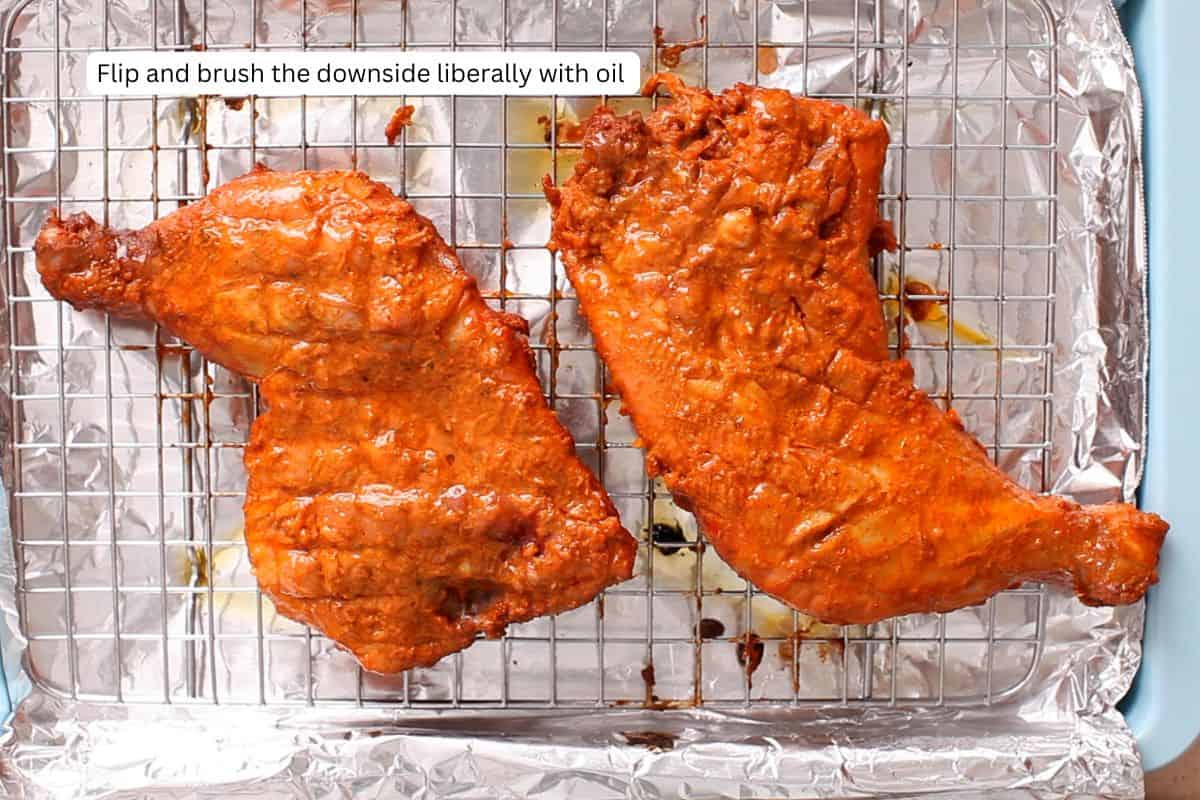 Chicken is flipped and the underside is brushed with oil.