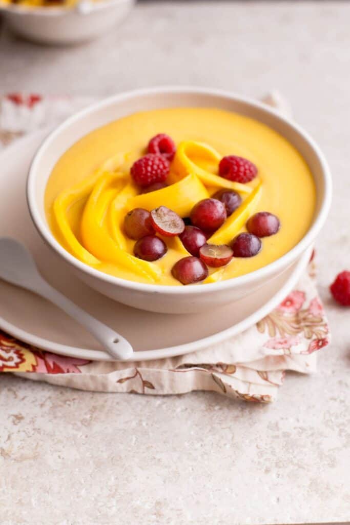 Side view of Indian fruit custard on a beige tile.