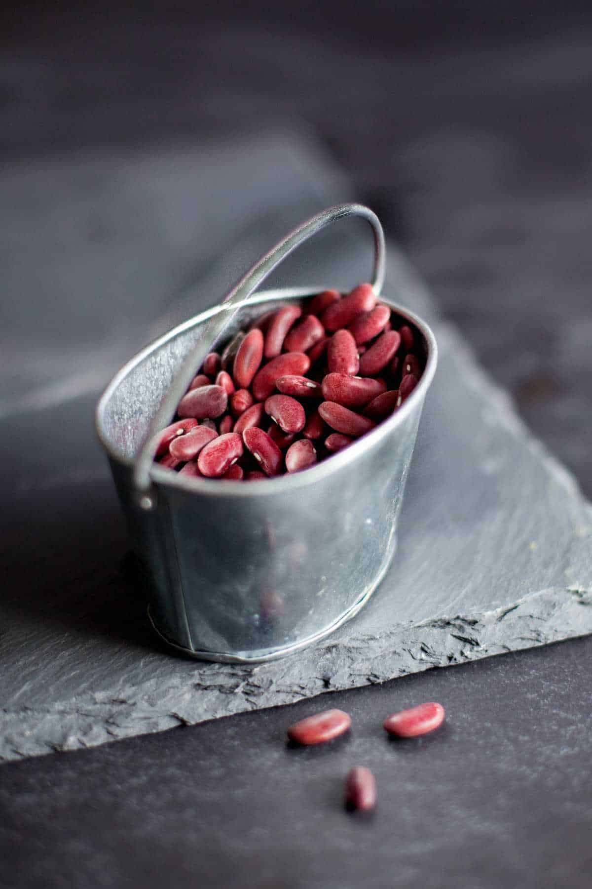 Dry rajma or dark red kidney beans in a small grey bucket.
