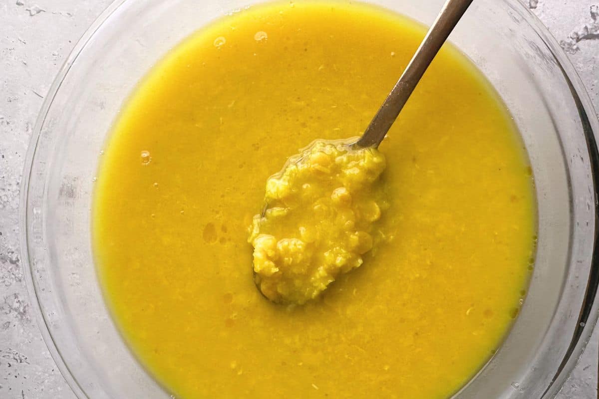 Cooked and mashed lentils in a glass bowl.